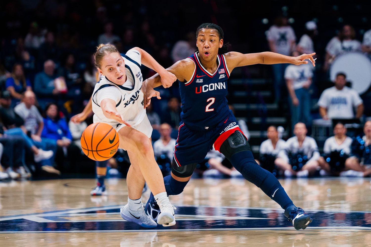 Basketball players dive and scramble for a loose ball during an intense game on the hardwood court.