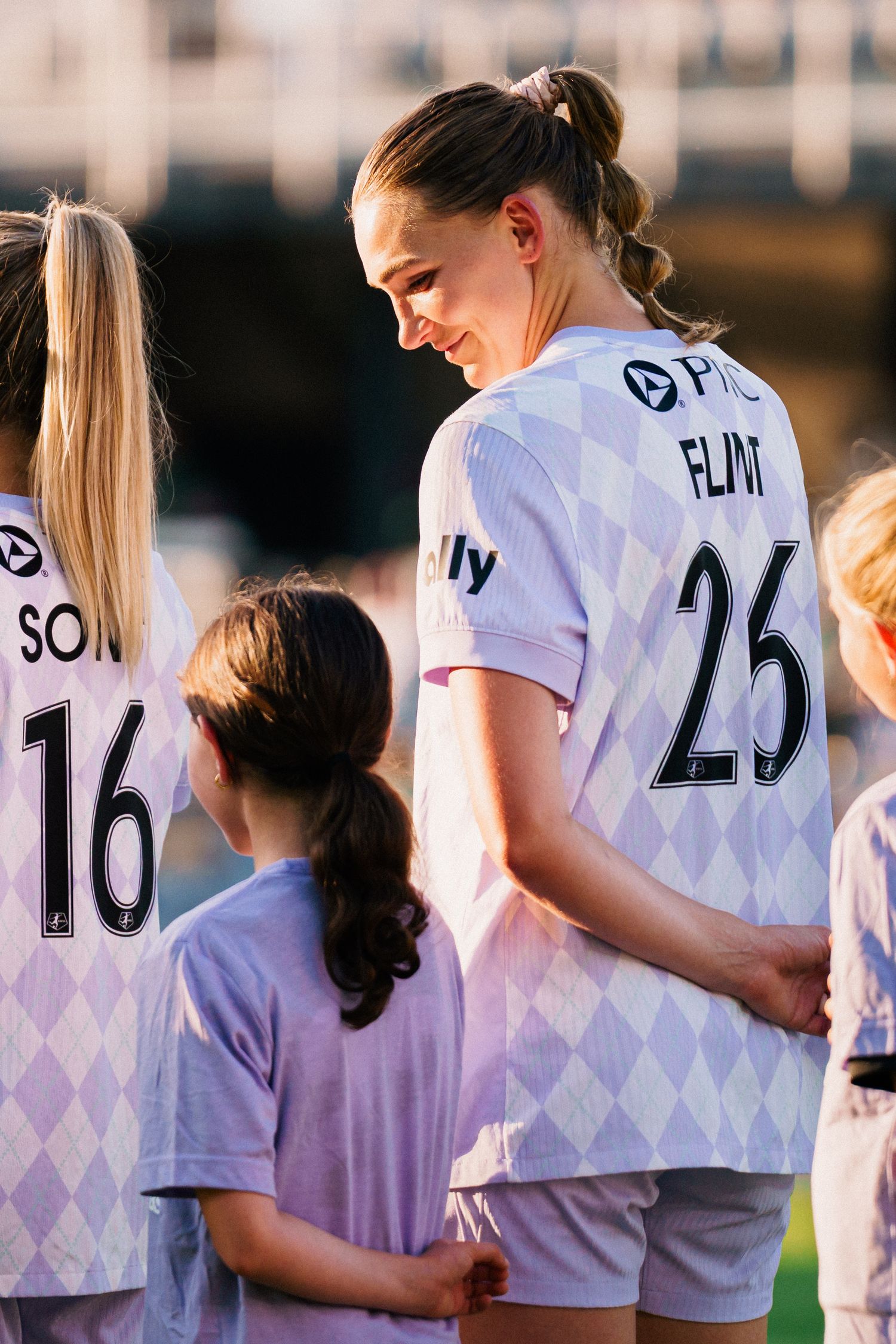 Soccer players wearing white jerseys with numbers stand together in a row during a team lineup.