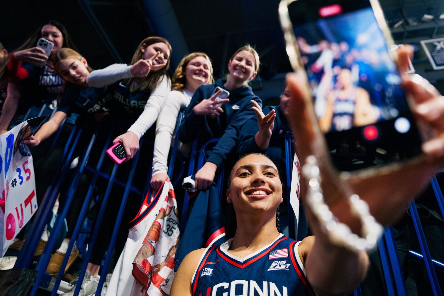 Basketball fans cheer and celebrate in the stands during an exciting game moment.