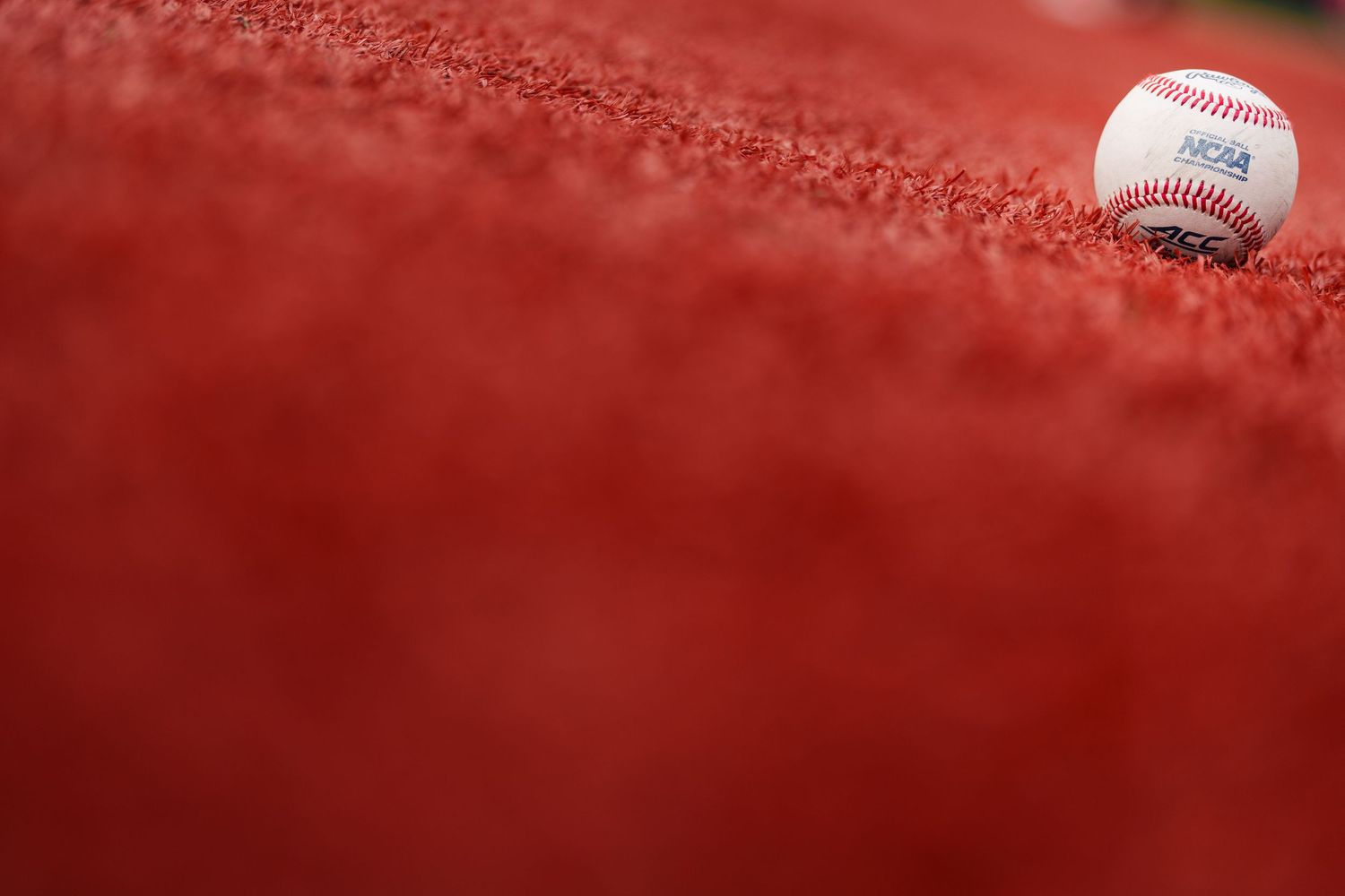 Macro detail shot of official baseball seams and stitching against red background.