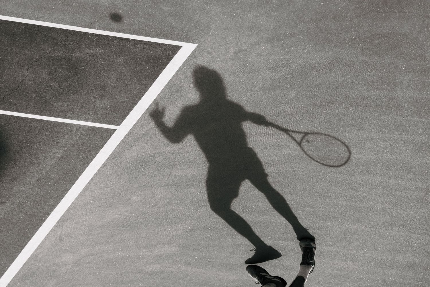 Black and white sequence of tennis player performing a serve motion on court, captured in multiple frames.