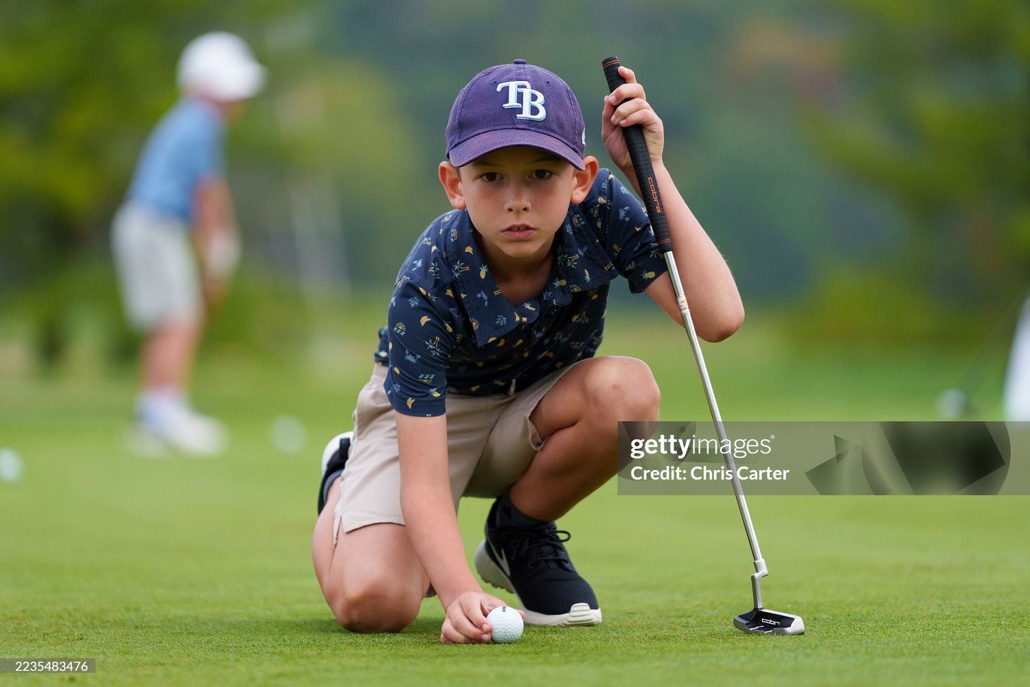 Golfer lines up a putt on the green during a competitive match, studying the break and slope of the course.