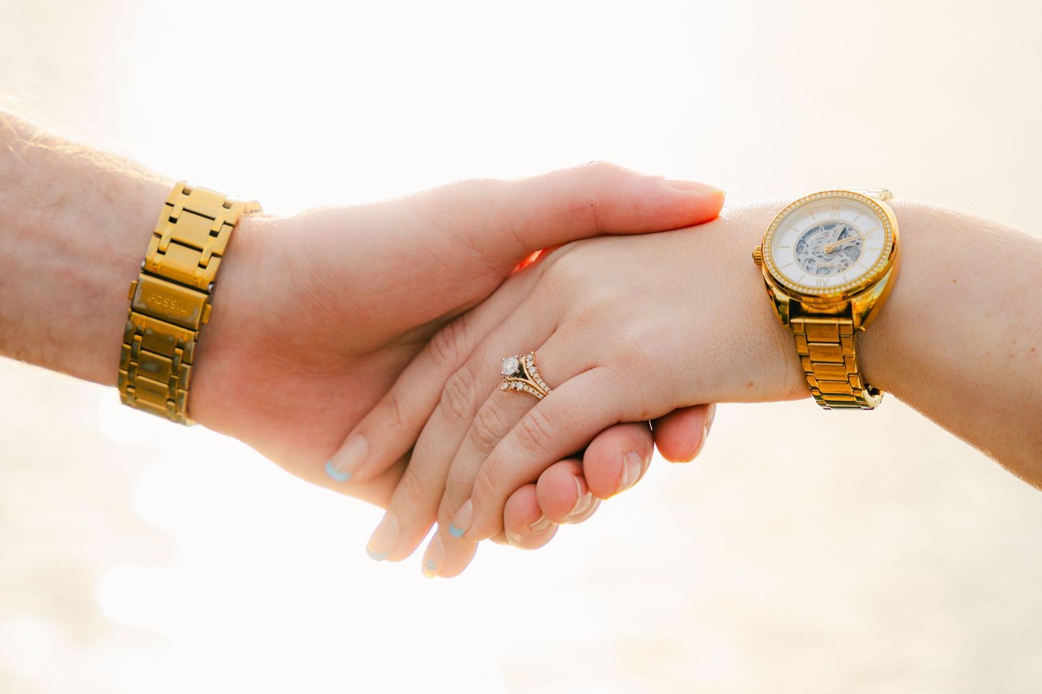 Close-up series of hands with gold watches joining together.