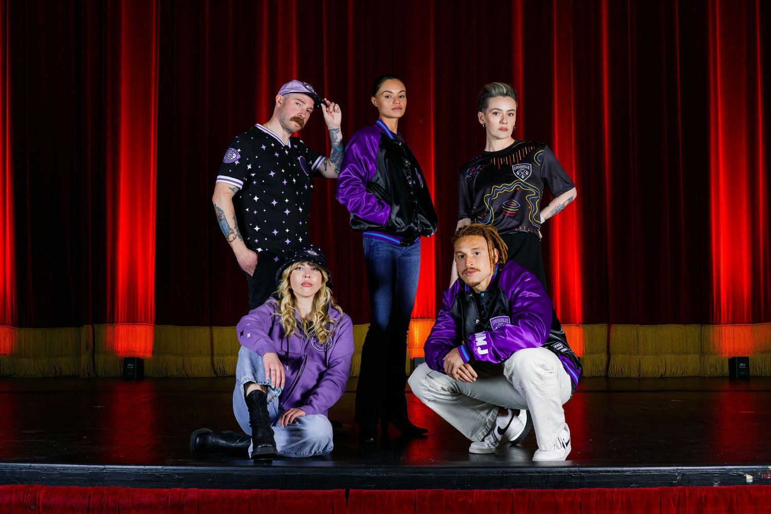 Stage performers dance during theatrical show with red lighting effects.
