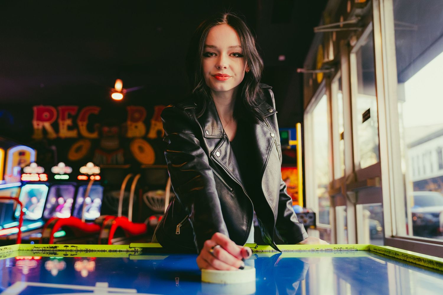 Professional photographer poses with camera equipment in retro style diner setting.