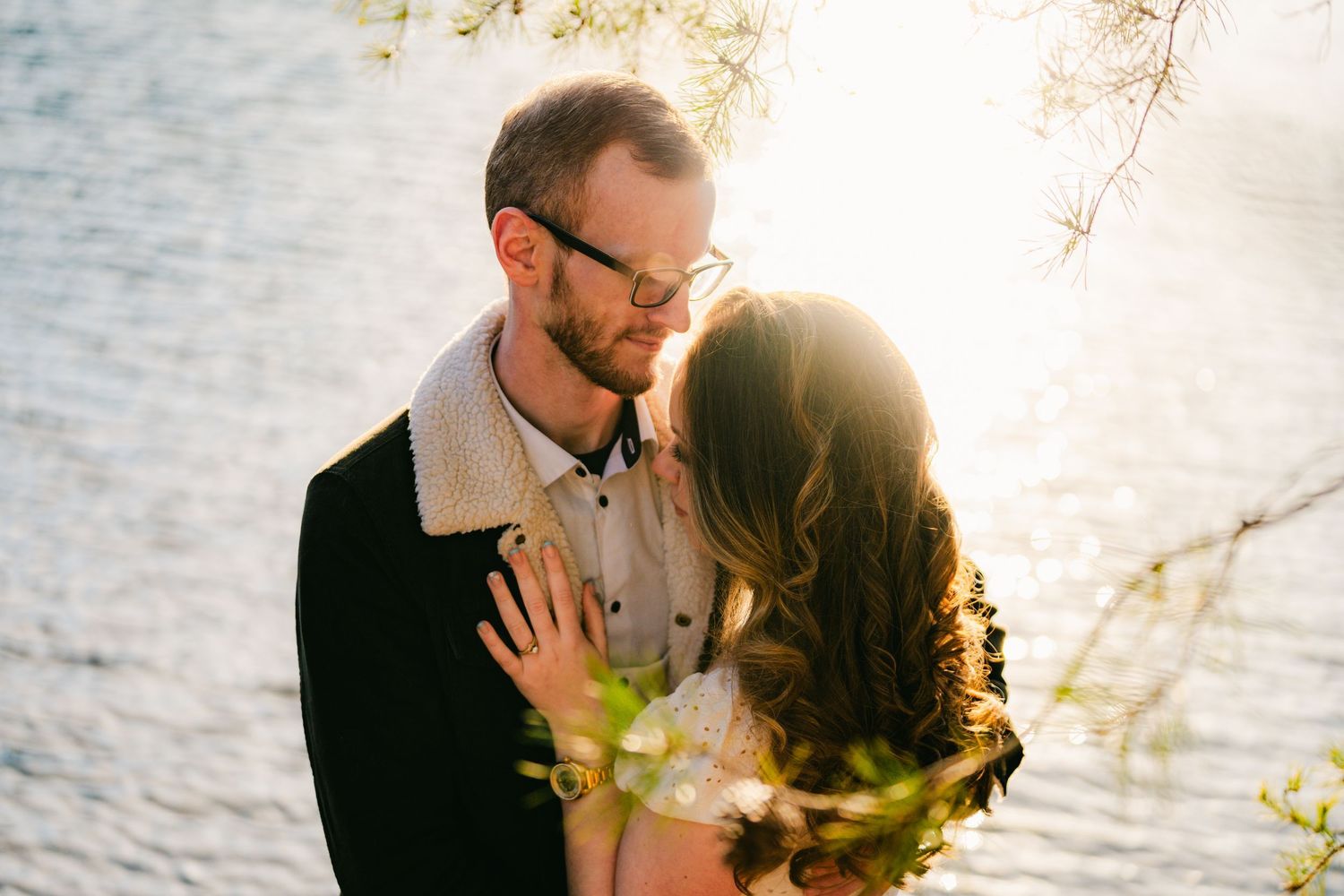 Romantic sunset portrait session by the water with golden light filtering through trees.
