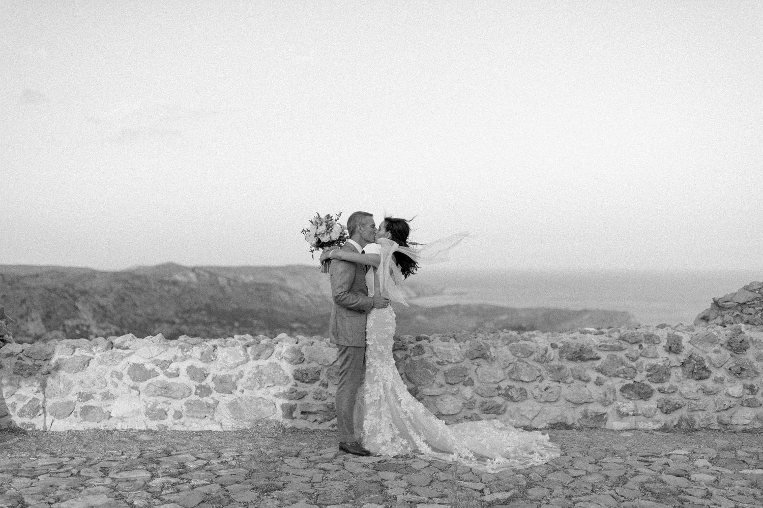Seven black and white film frames show destination wedding photographs at a scenic mountain or hillside location.