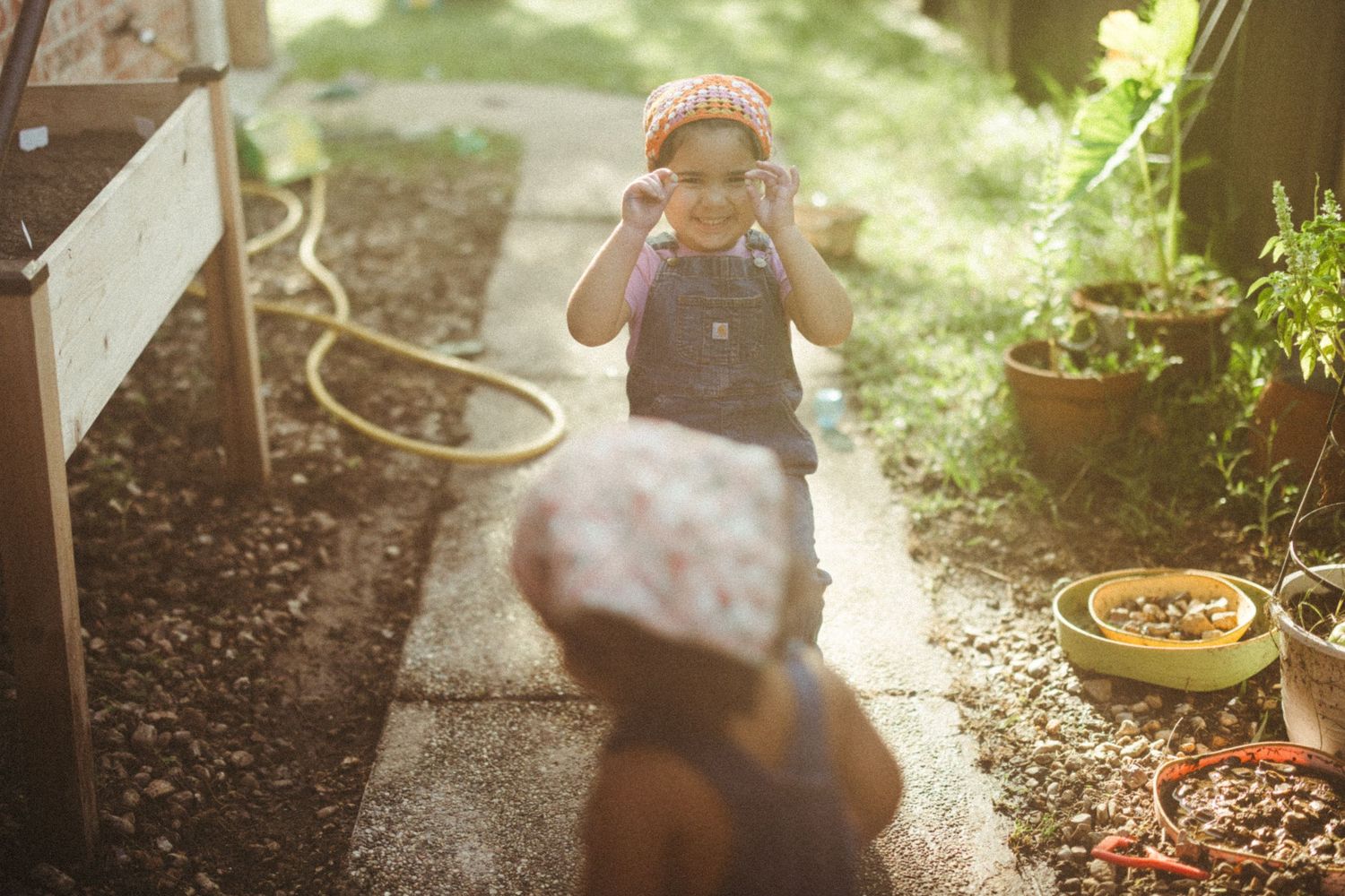 A sunlit garden path with potted plants and shadows creates a warm nostalgic summer scene.