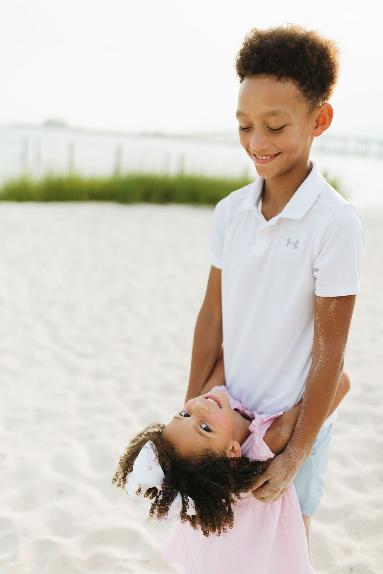 Siblings playing and laughing together on pristine white sand beach.