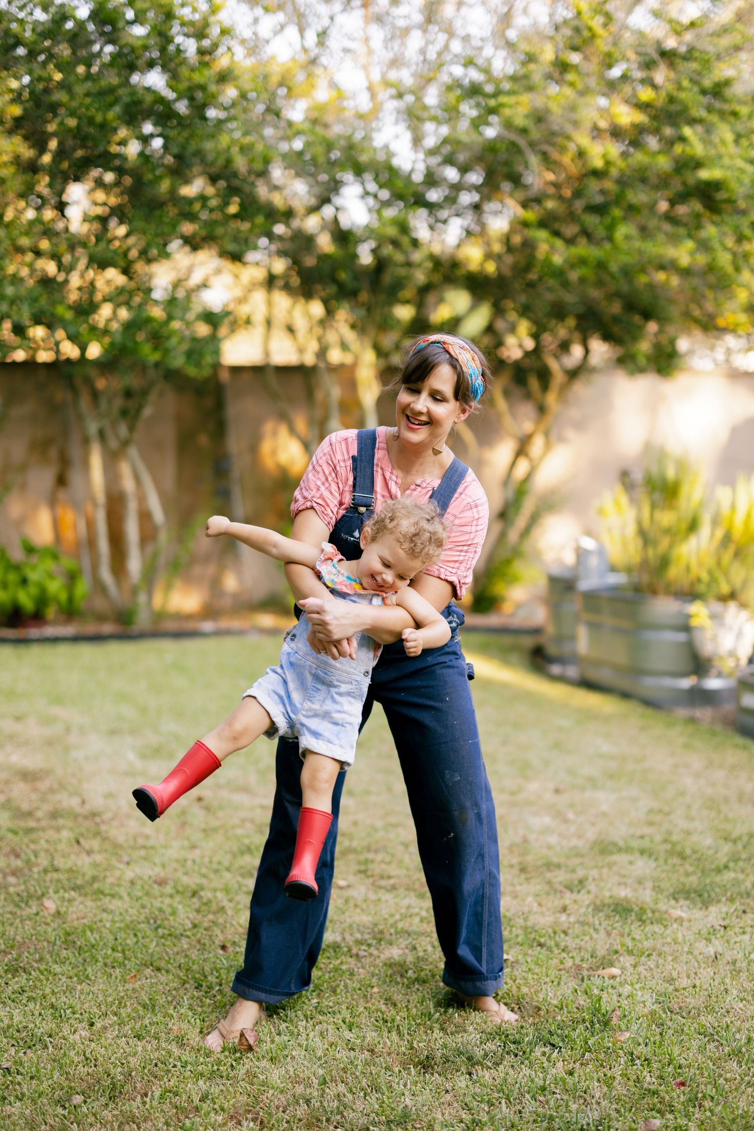 Lively outdoor playtime on a grassy lawn with denim overalls and pink clothing.