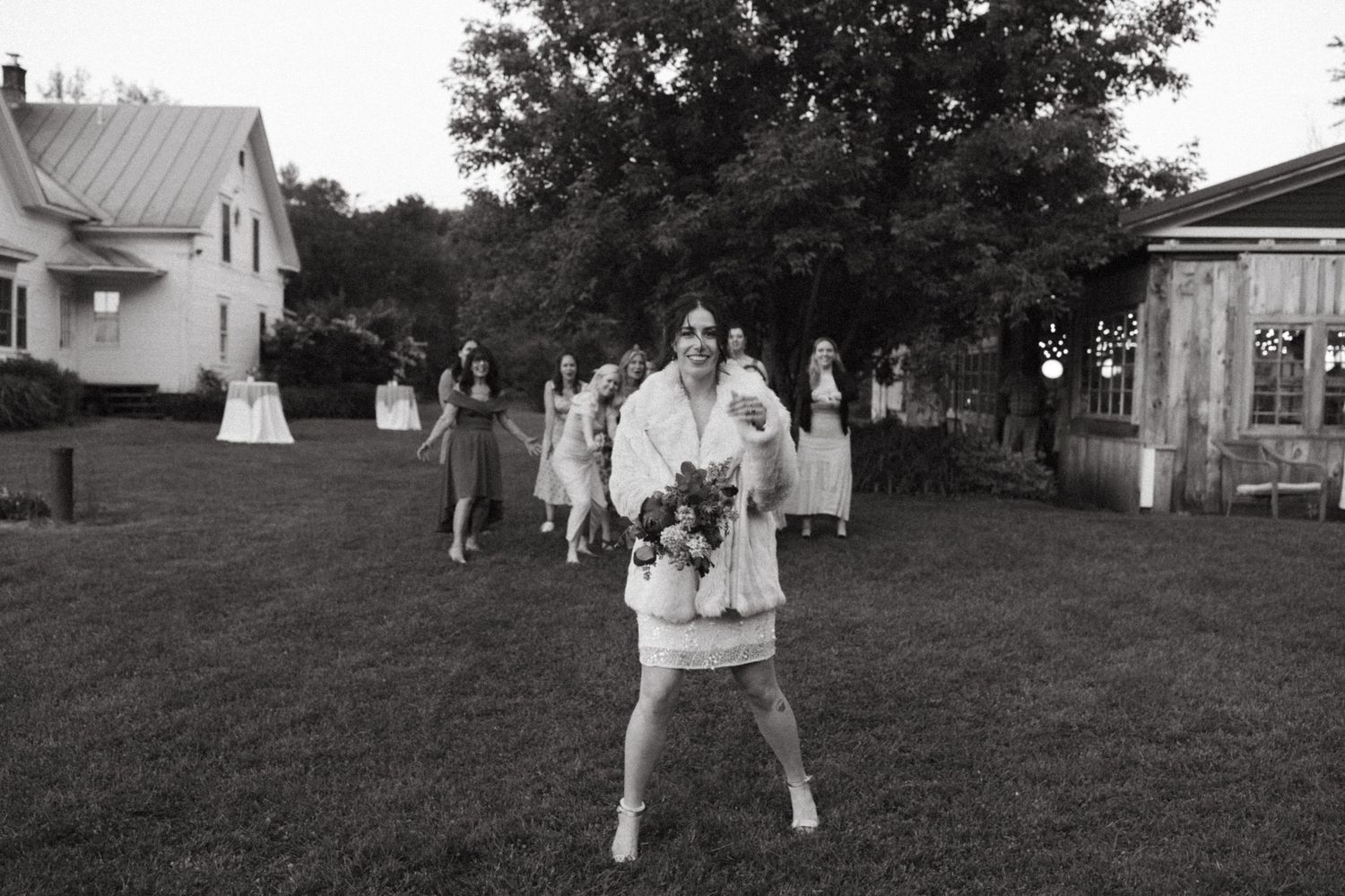 A black and white series of seven photographs showing people playing outside in a grassy yard.