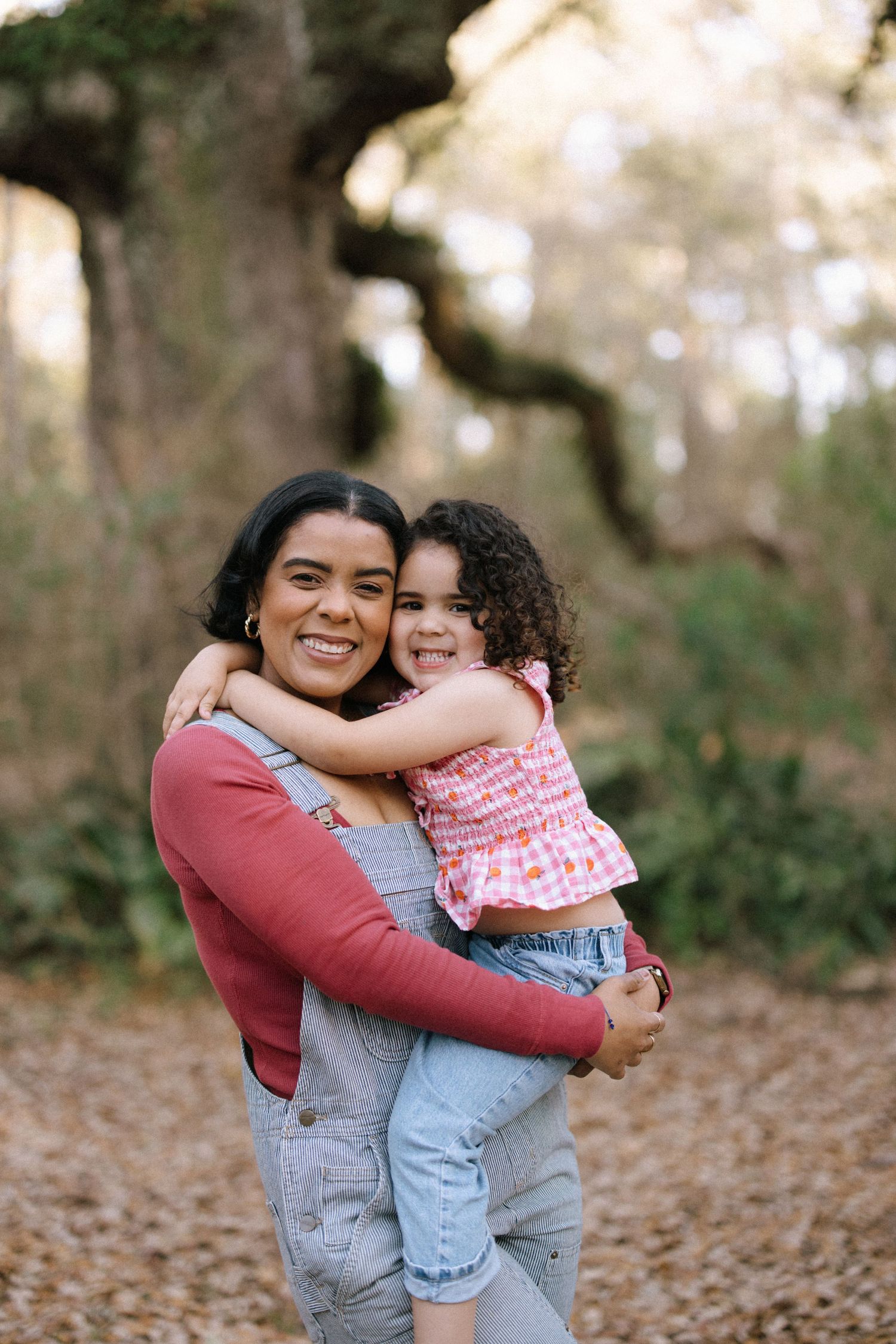 Two people sharing a warm embrace and smiling while standing among fallen autumn leaves outdoors.