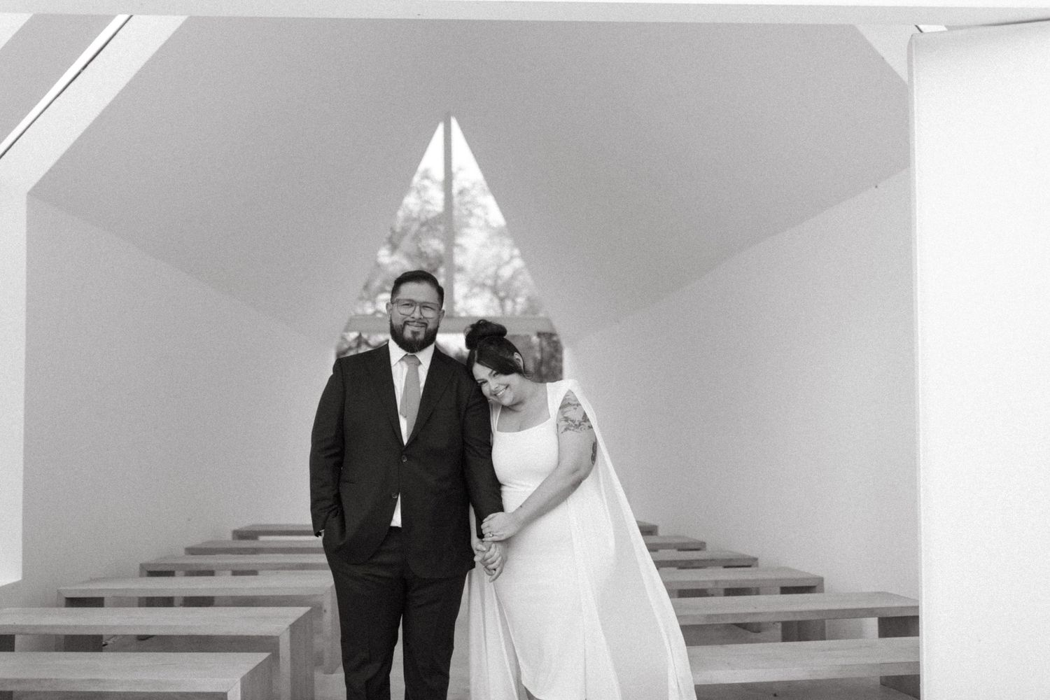 A newlywed couple poses at different locations in a church during their black and white wedding celebration.