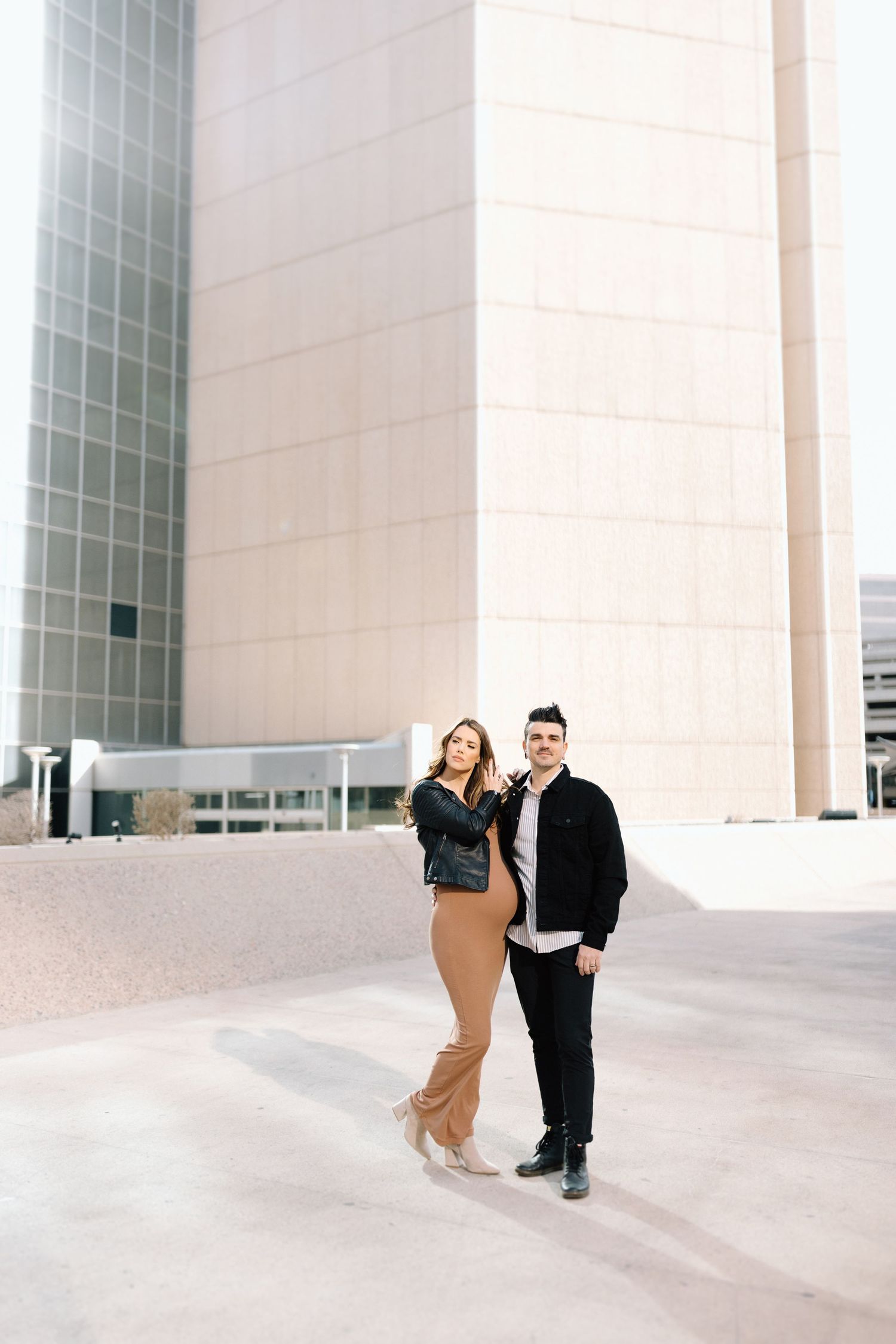 Stylish couple poses against modern architectural building with white walls and geometric lines in urban setting.