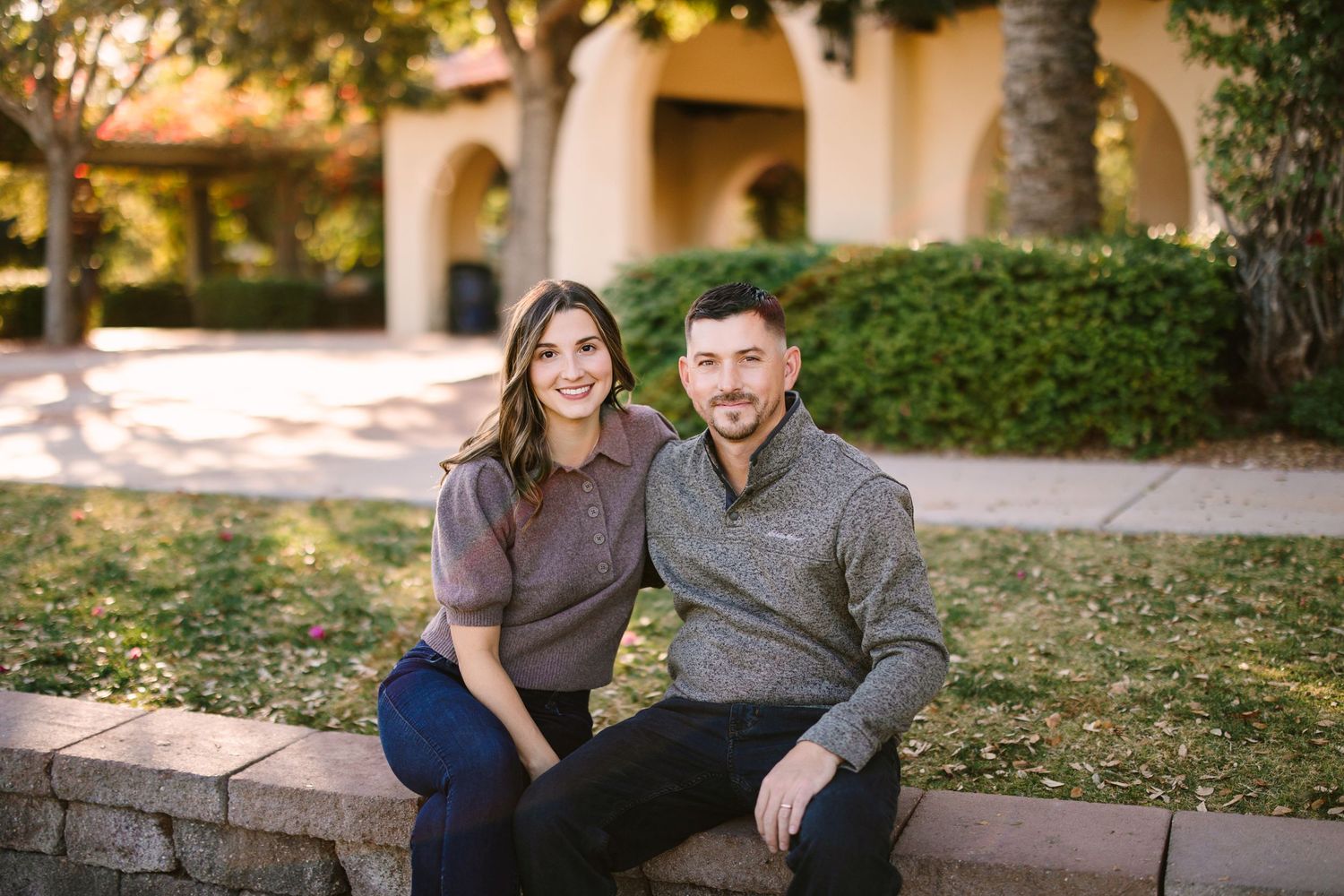 A couple shares a tender moment while sitting together on stone steps during an outdoor photo session.