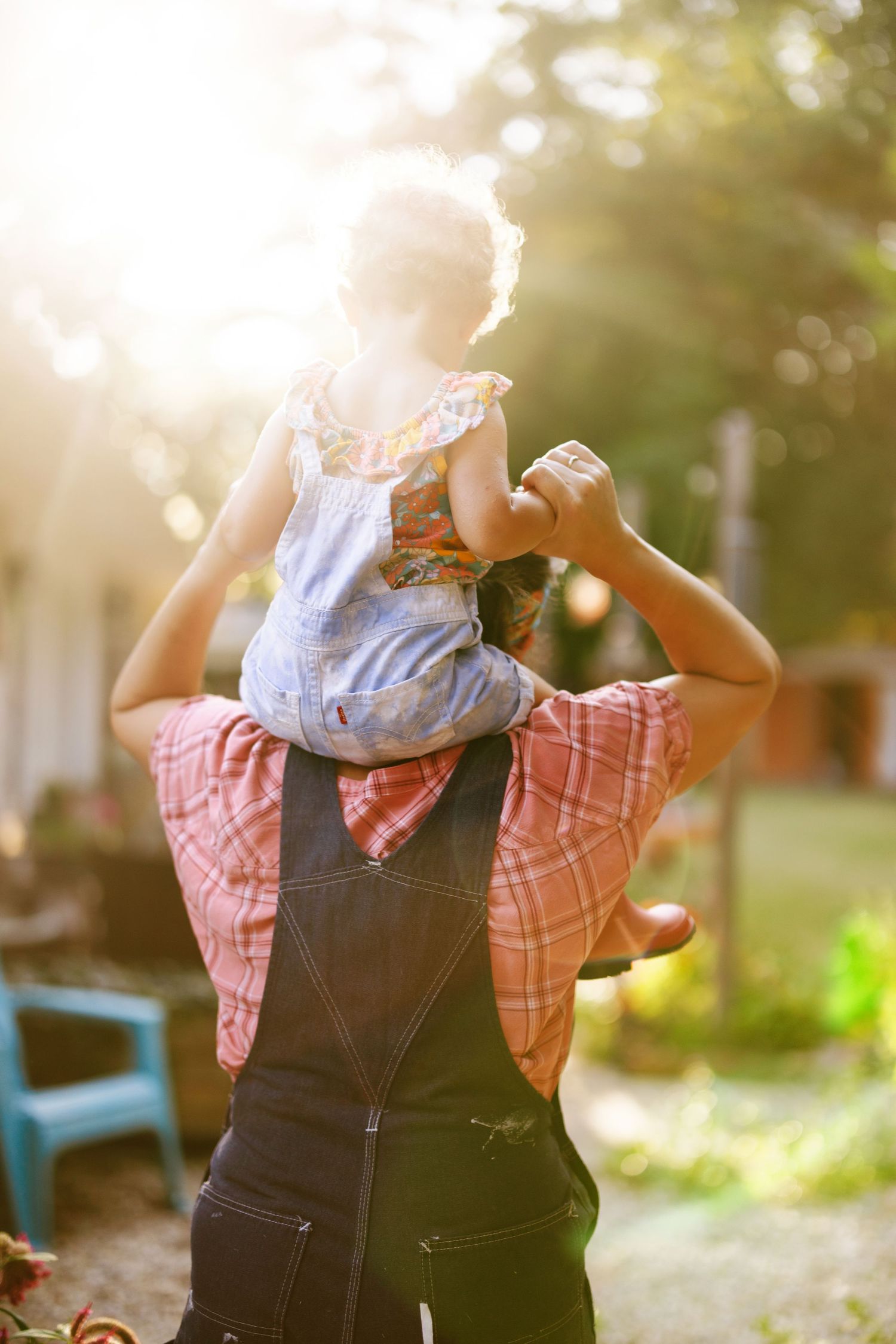 Playful scene in a backyard garden with overalls against golden sunlight.