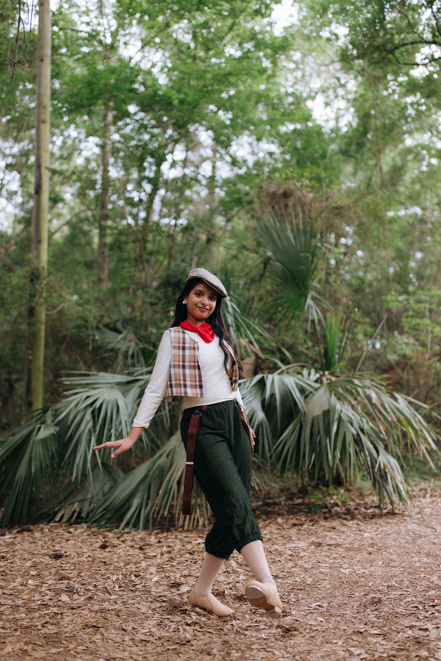 A stylish modern outfit captured in a natural setting with palm fronds and pine trees in the background.