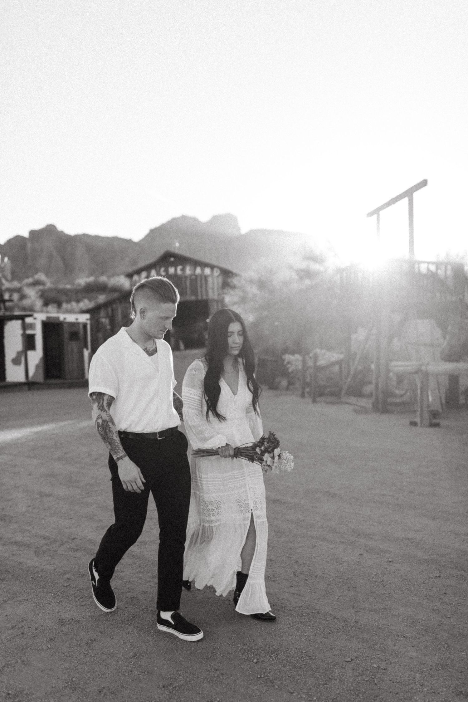 A romantic couple shares a tender dance together on a grassy field at sunset in black and white.