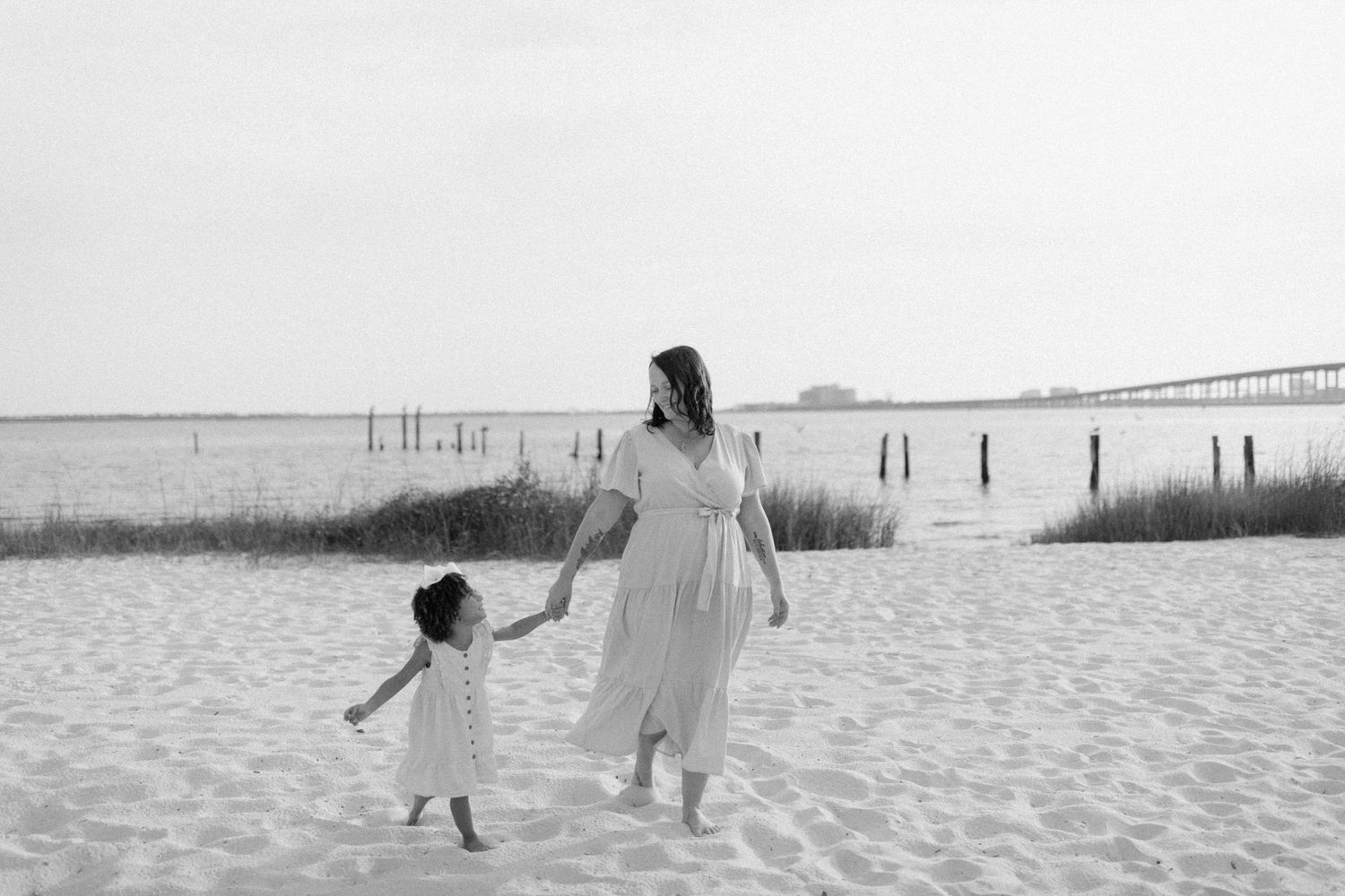 Black and white photo captures playful silhouettes of people running and playing on a beach.