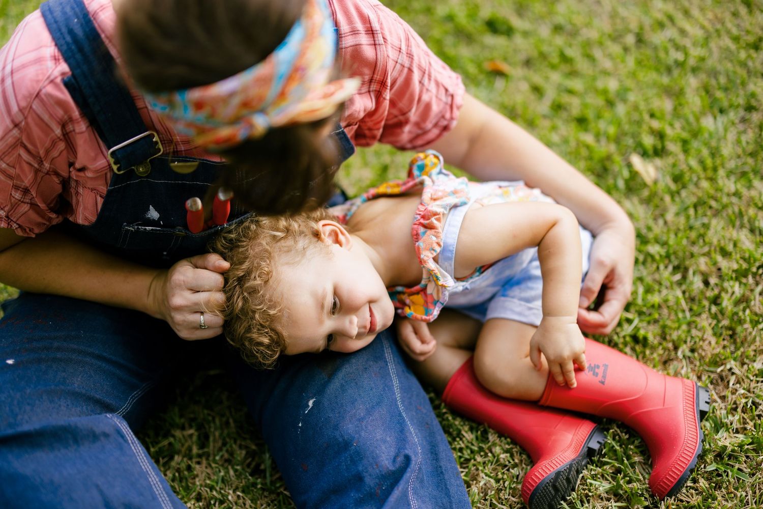 Playful moment on green grass with red boots in the summer sun.