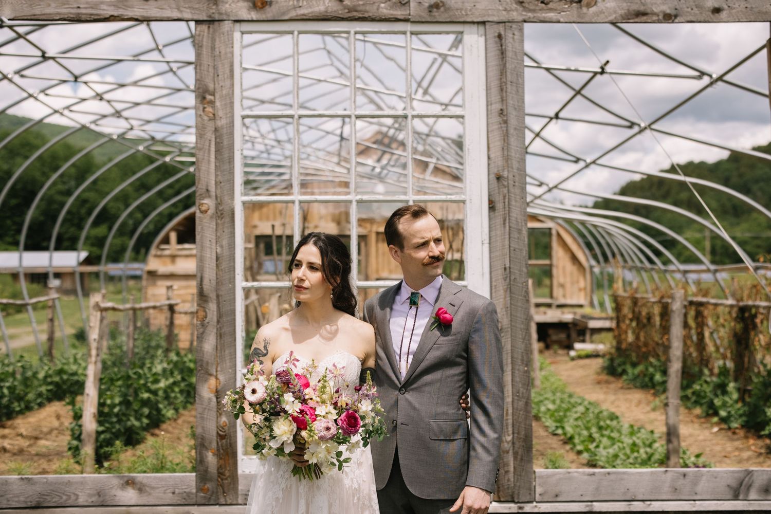 A couple celebrates their wedding day inside a rustic greenhouse surrounded by natural light and lush greenery.