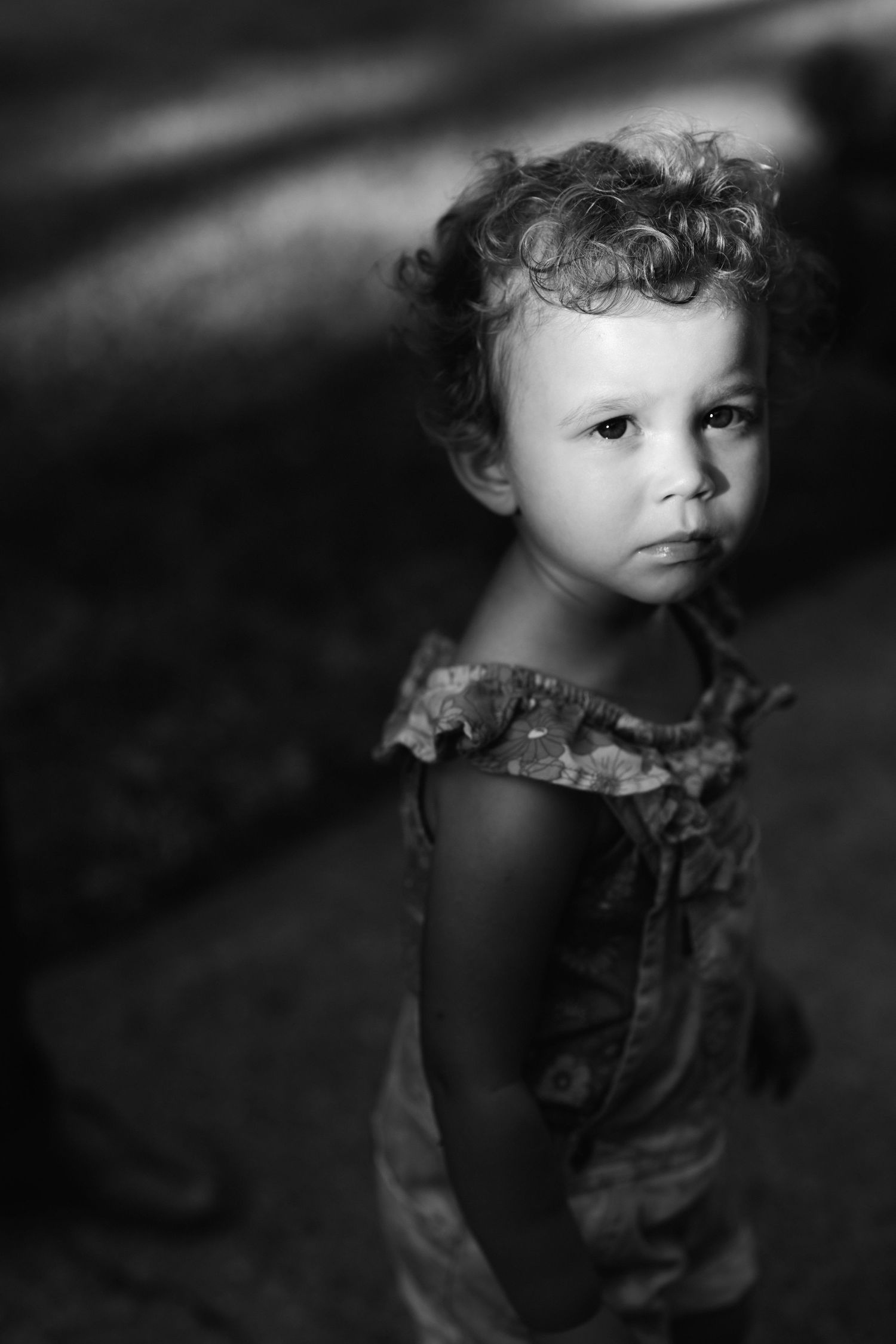 Black and white artistic portrait series of a young child with curly hair in patterned clothing.