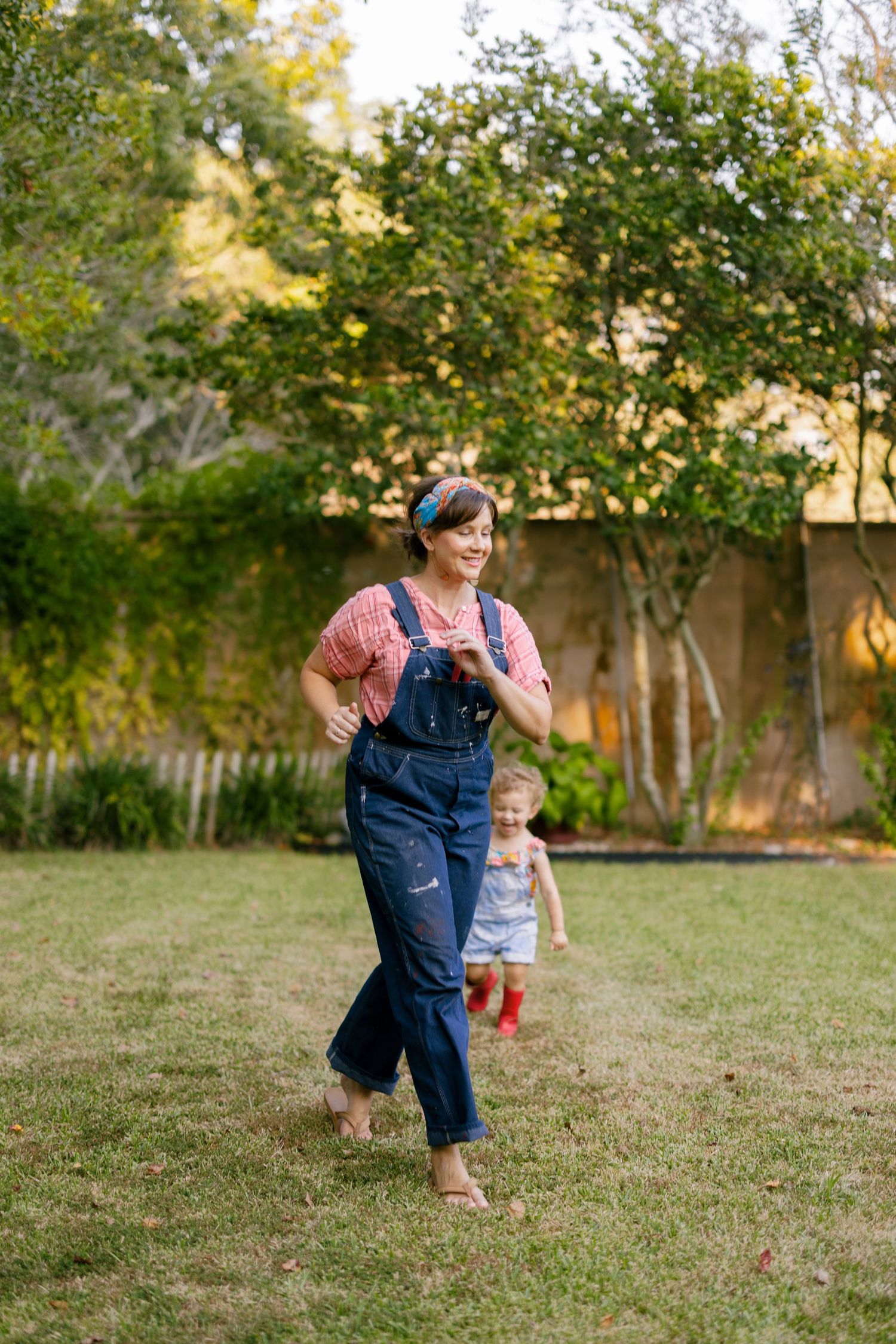 Active playtime in a backyard garden with overalls and casual clothing during late afternoon light.