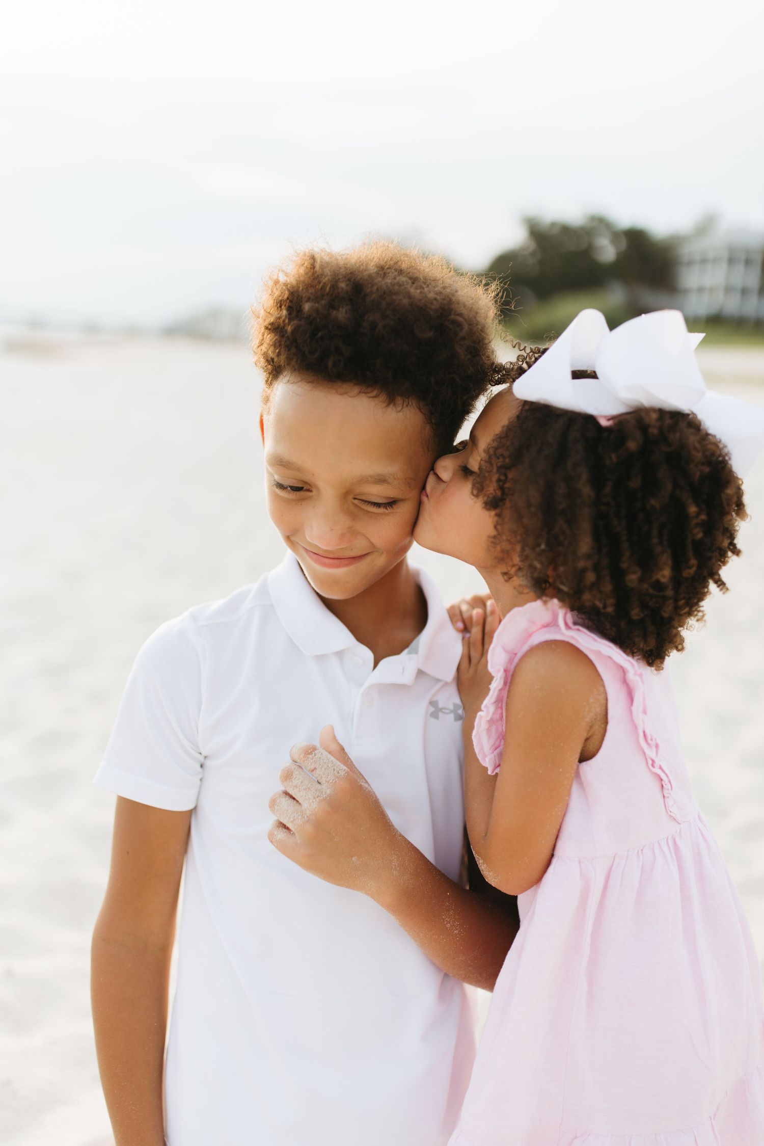 Two young siblings share tender moment together on sunny beach.