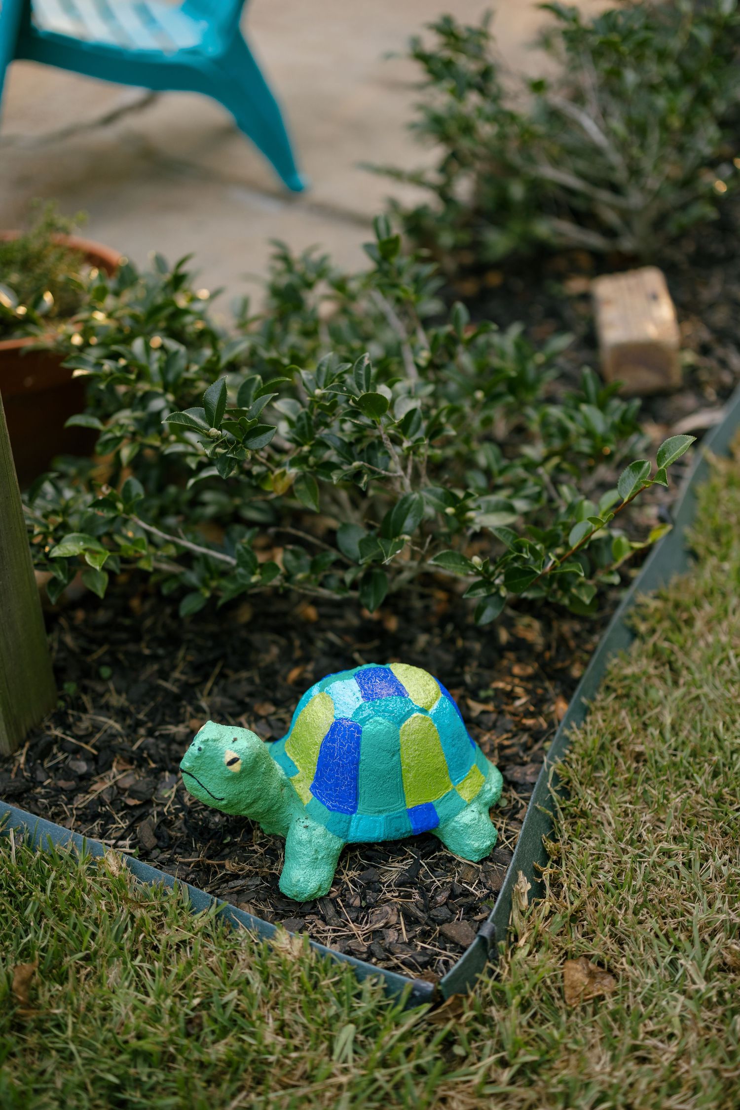 Decorative blue and green turtle garden ornaments nestled in the grass near plants.