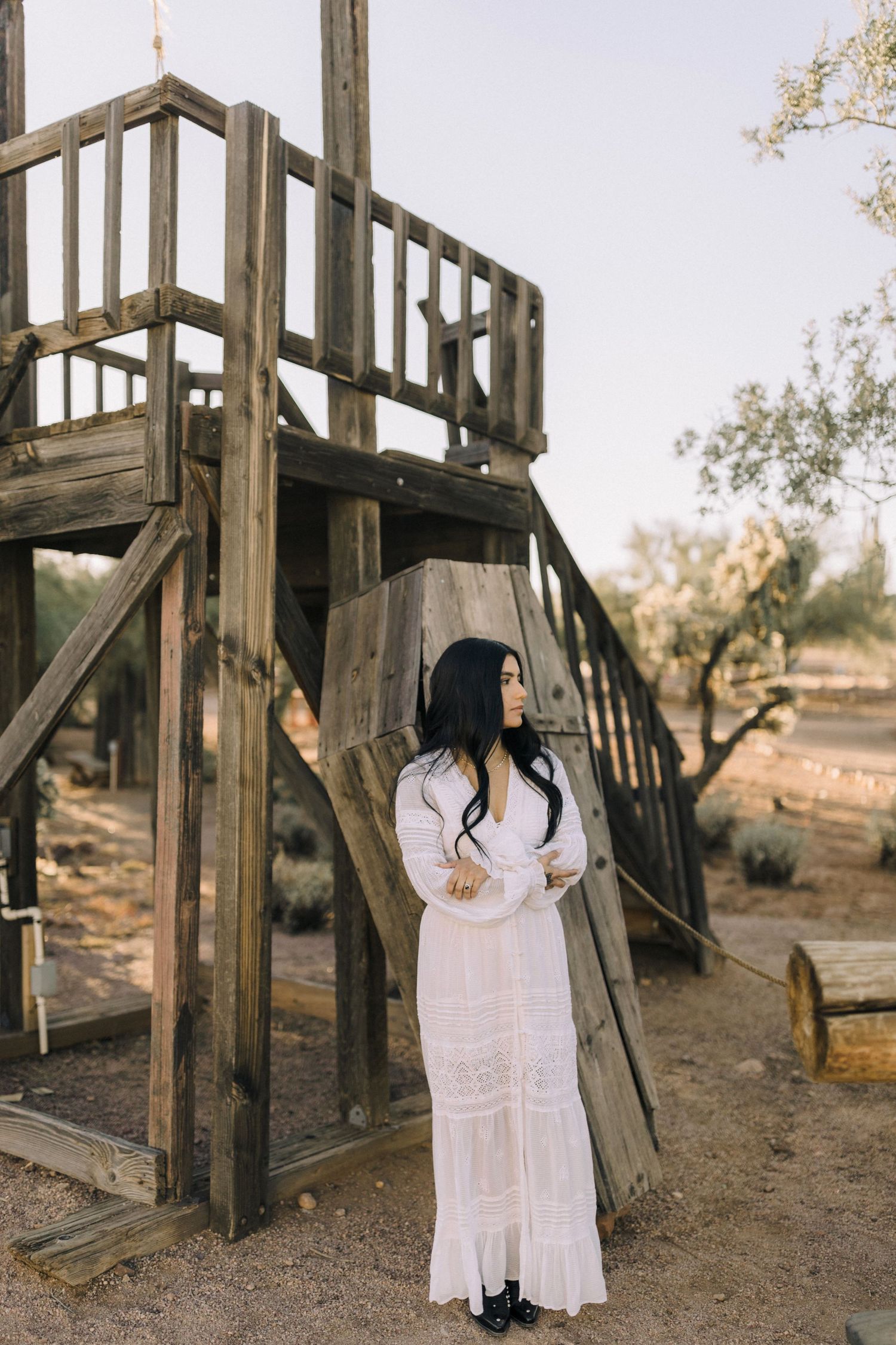 An artistic photo series showing figures in white dresses against a rustic wooden playground structure at sunset.