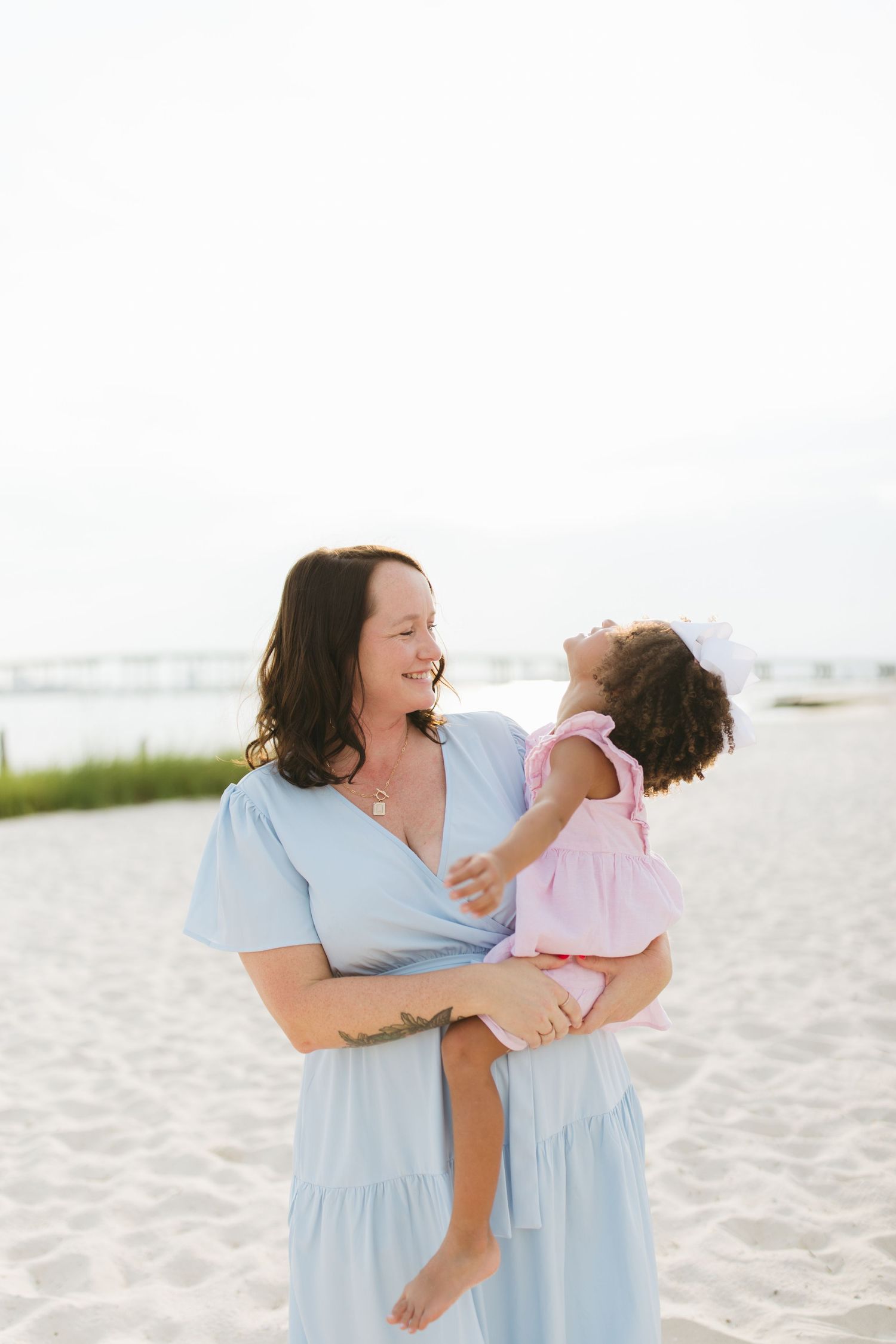 A tender family moment of playful interaction and laughter on a bright sandy beach.
