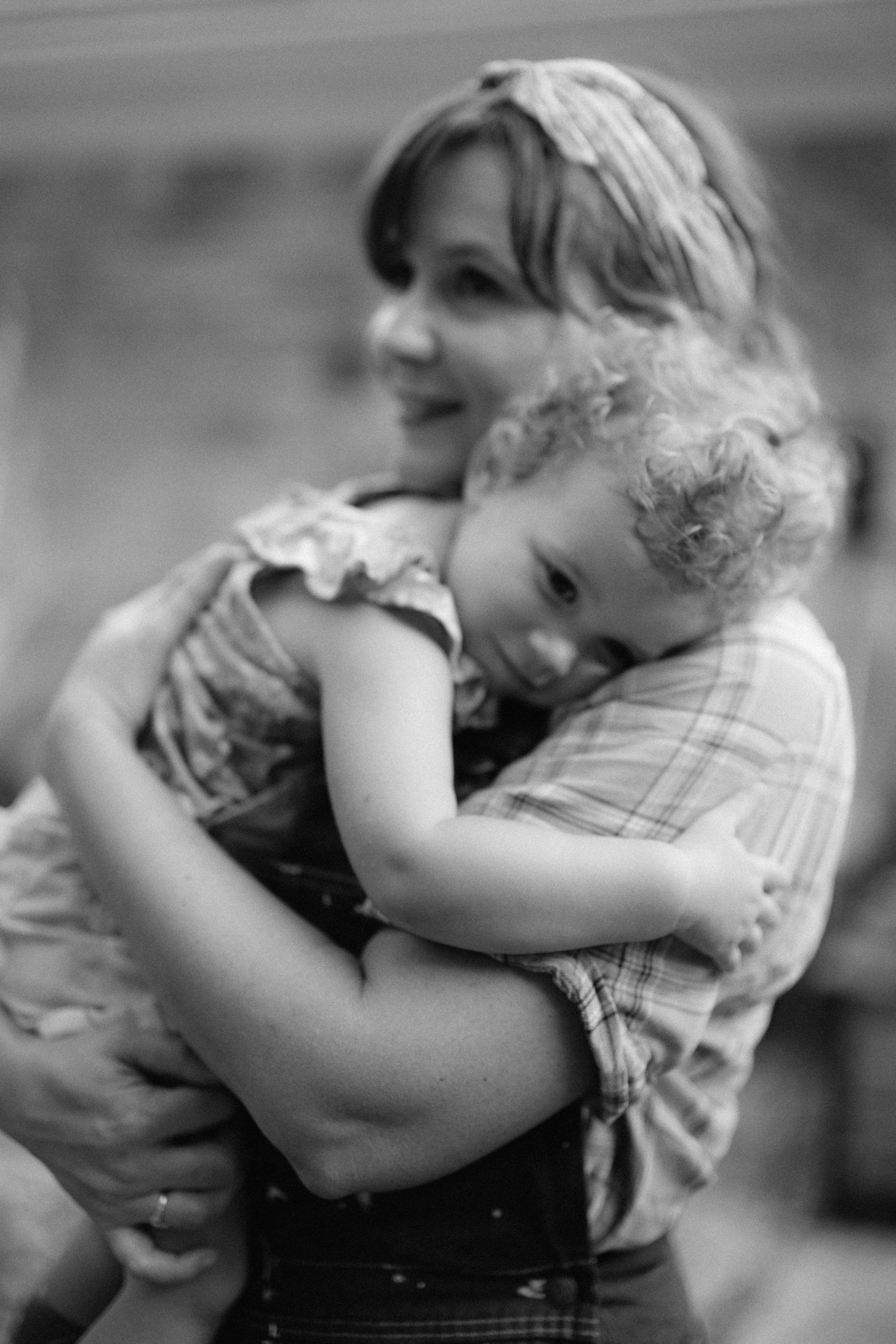 Parent hugging and snuggling young child in a tender black and white portrait series.