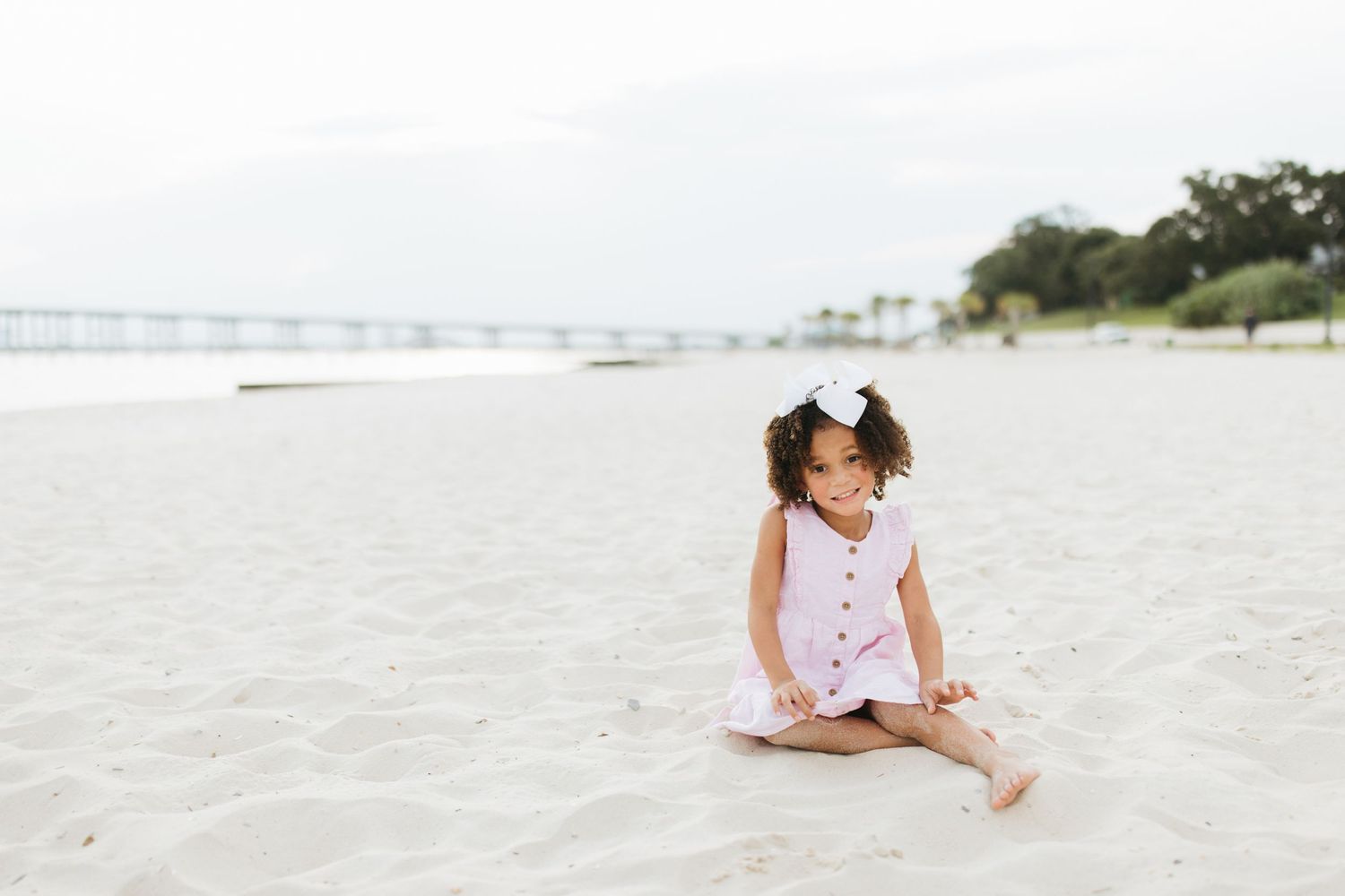 Mother and child laying together on white sand beach during a casual photo session.