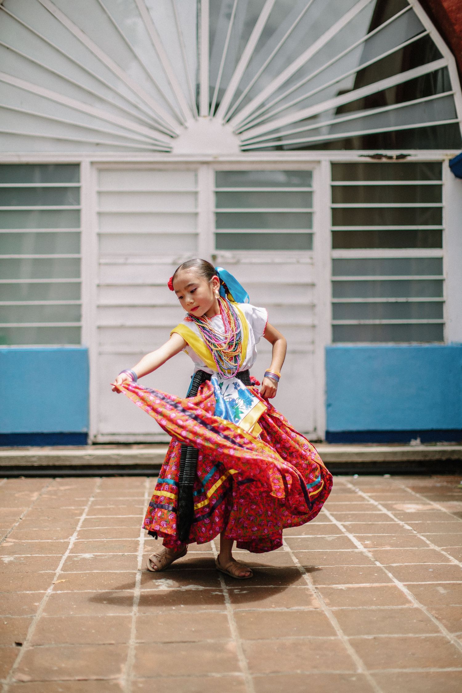 A dancer in a vibrant red traditional dress spins gracefully across tiled floor in a four-panel motion sequence.