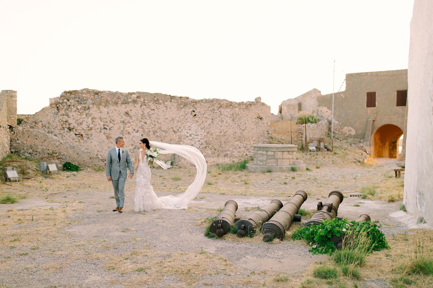 Ancient stone fortress ruins with archways and walls stand against an arid mountain landscape.