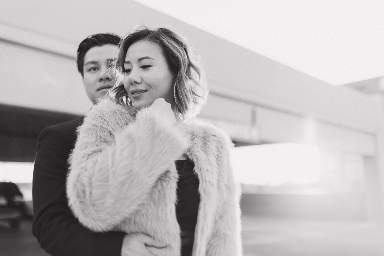 Two people share an intimate black and white winter moment wearing cozy coats outdoors.
