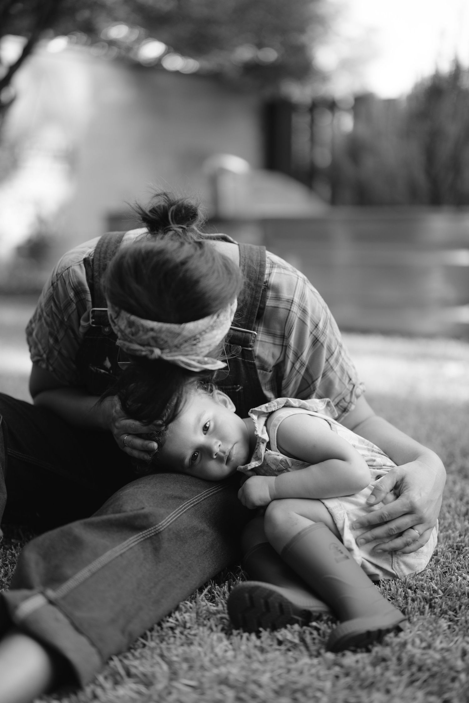 Black and white photo of someone sleeping peacefully on grassy ground in a curled position.