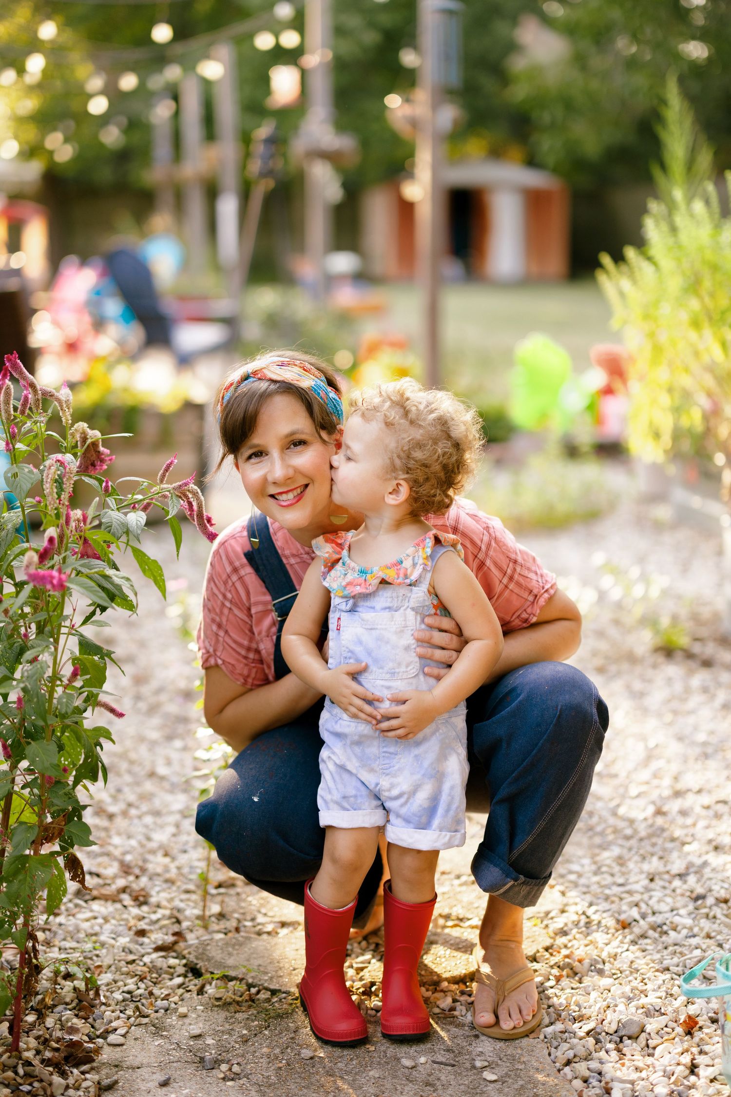 Sweet tender moments between parent and toddler outdoors in colorful seasonal boots on garden pathway.