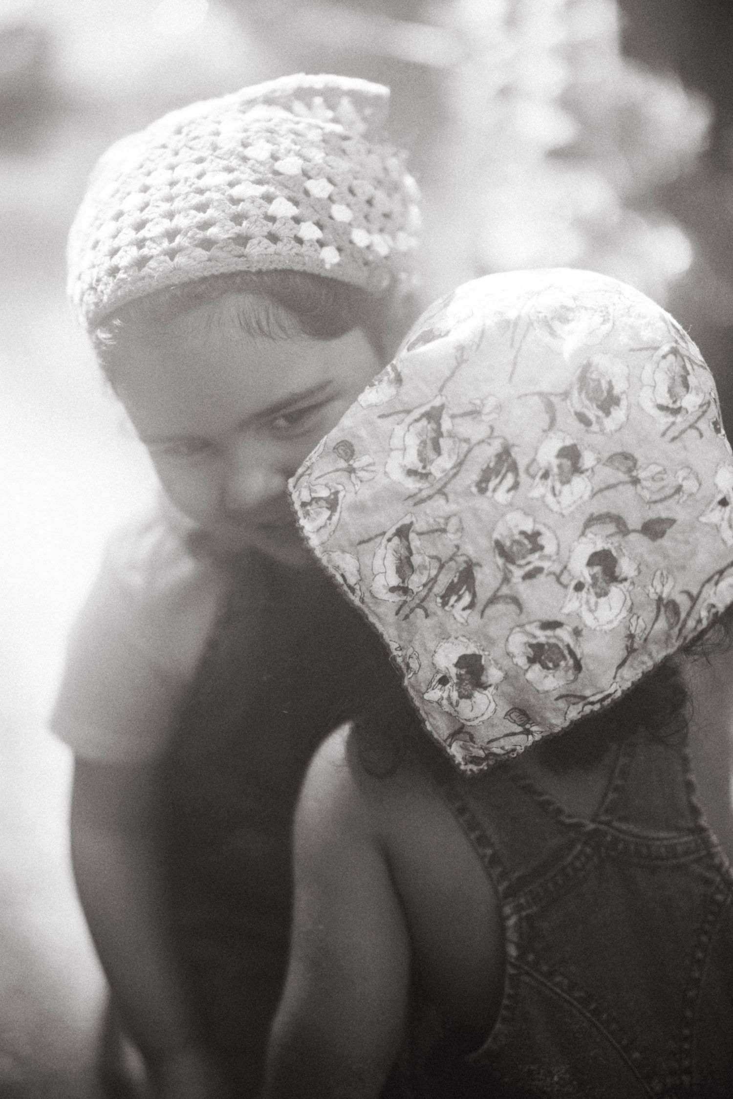 Black and white artistic portrait showing two children wearing patterned head coverings in soft focus.
