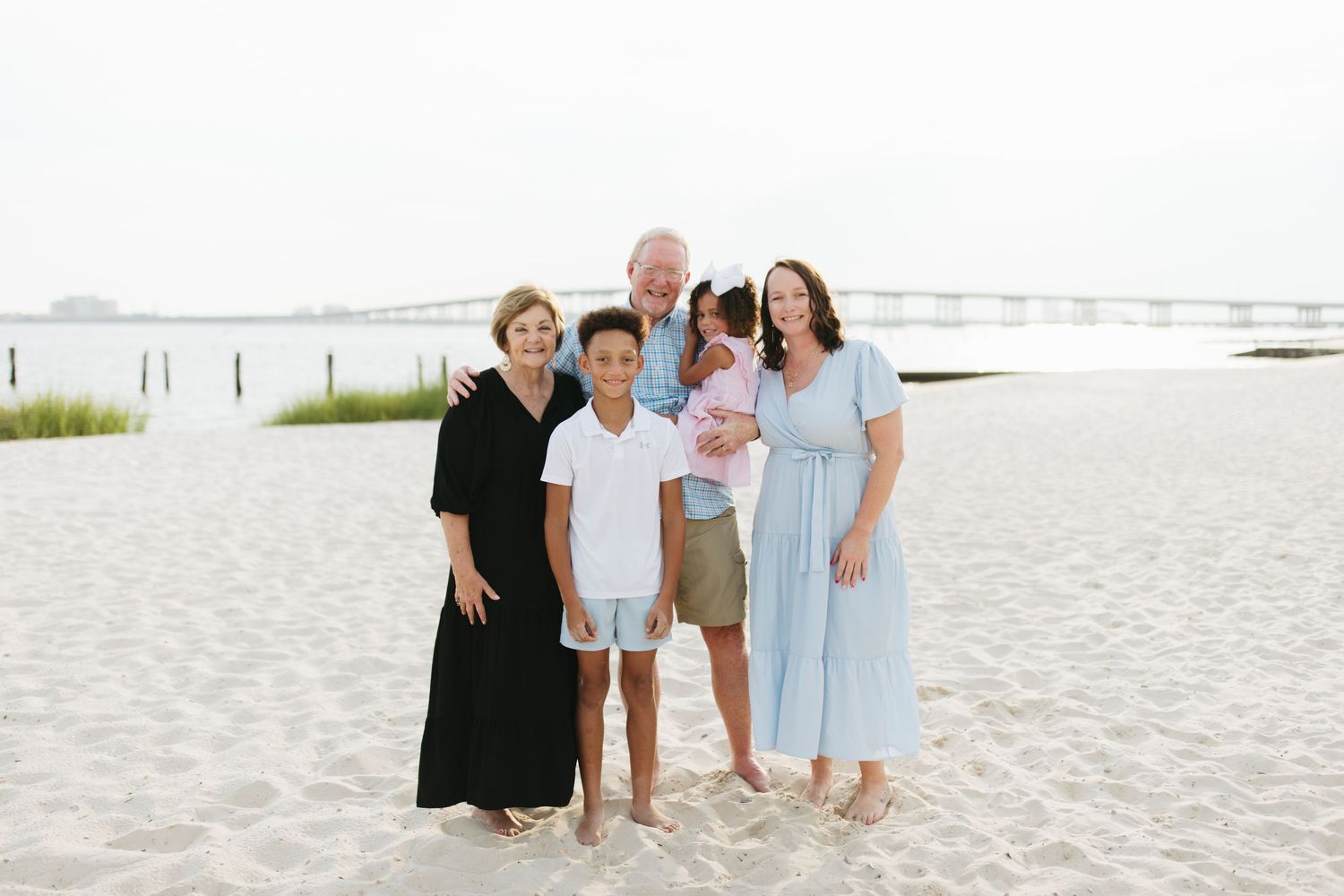 A group enjoying a sunny day on a white sandy beach with ocean waves and dunes in the background.