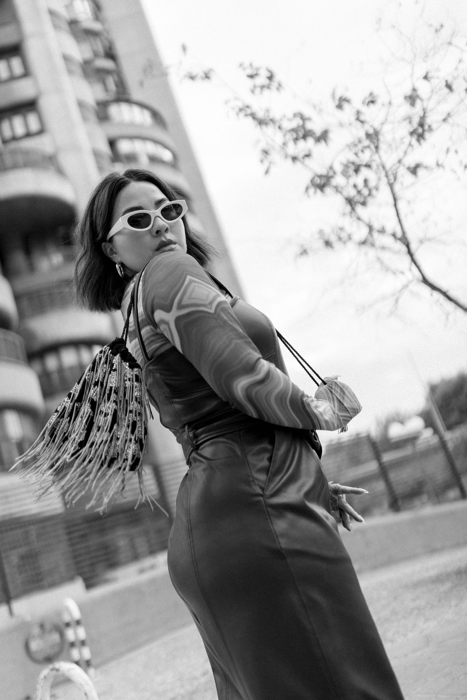 A series of black and white photos showing a person in sunglasses and braids leaning back in dynamic poses.