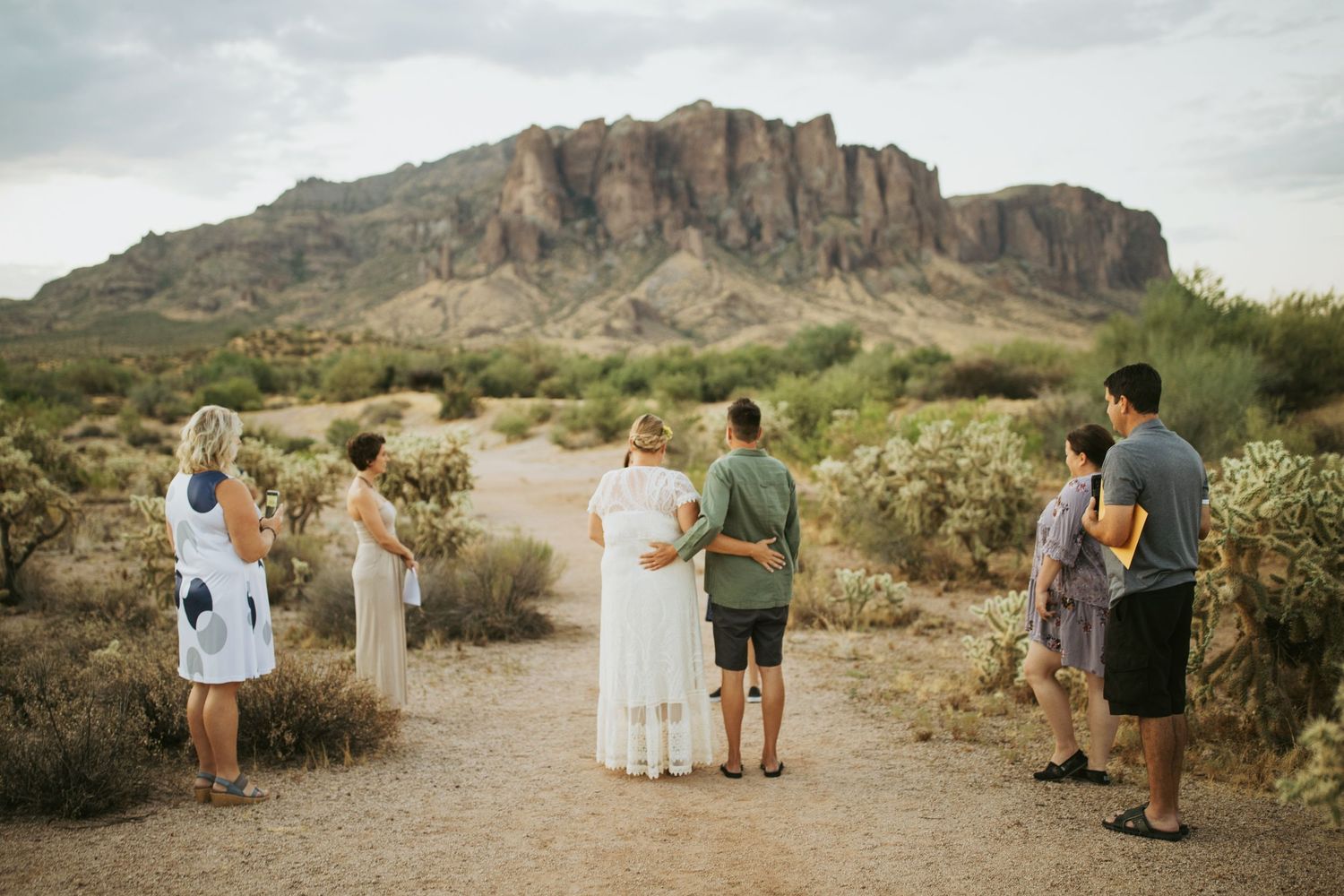 A scenic photography session takes place with a group in casual attire against the dramatic backdrop of desert mountains.