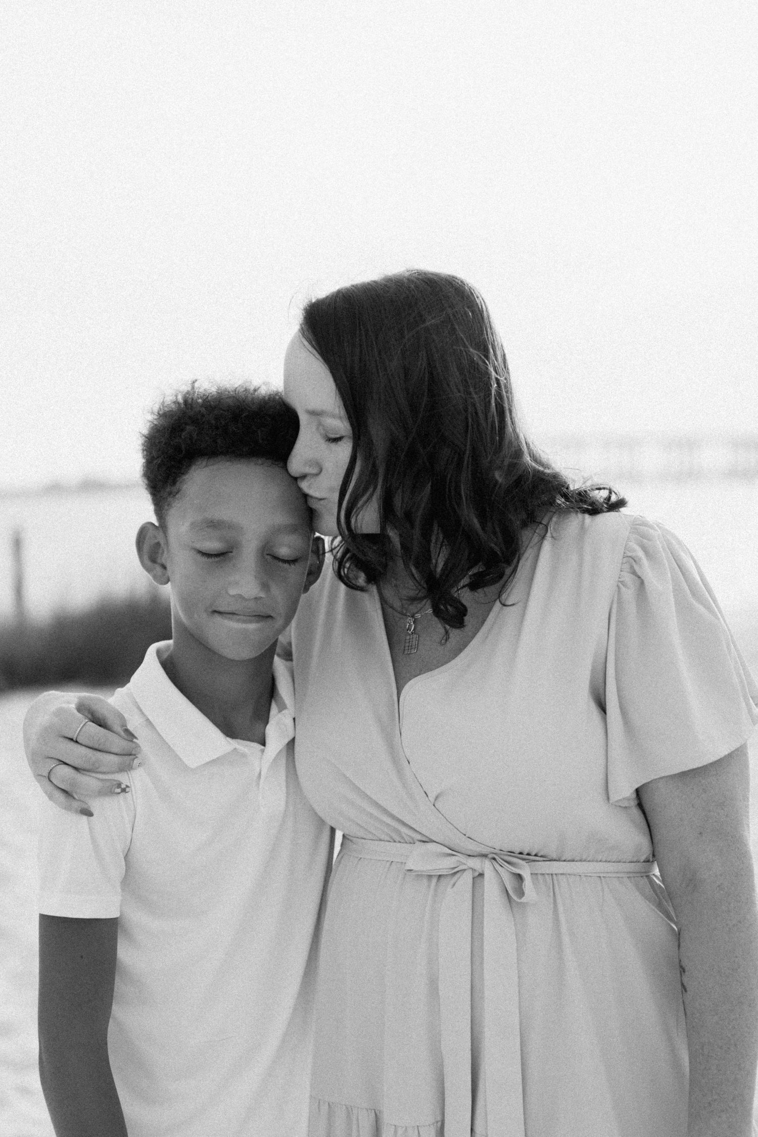 Intimate black and white portrait showing tender family affection in soft lighting.