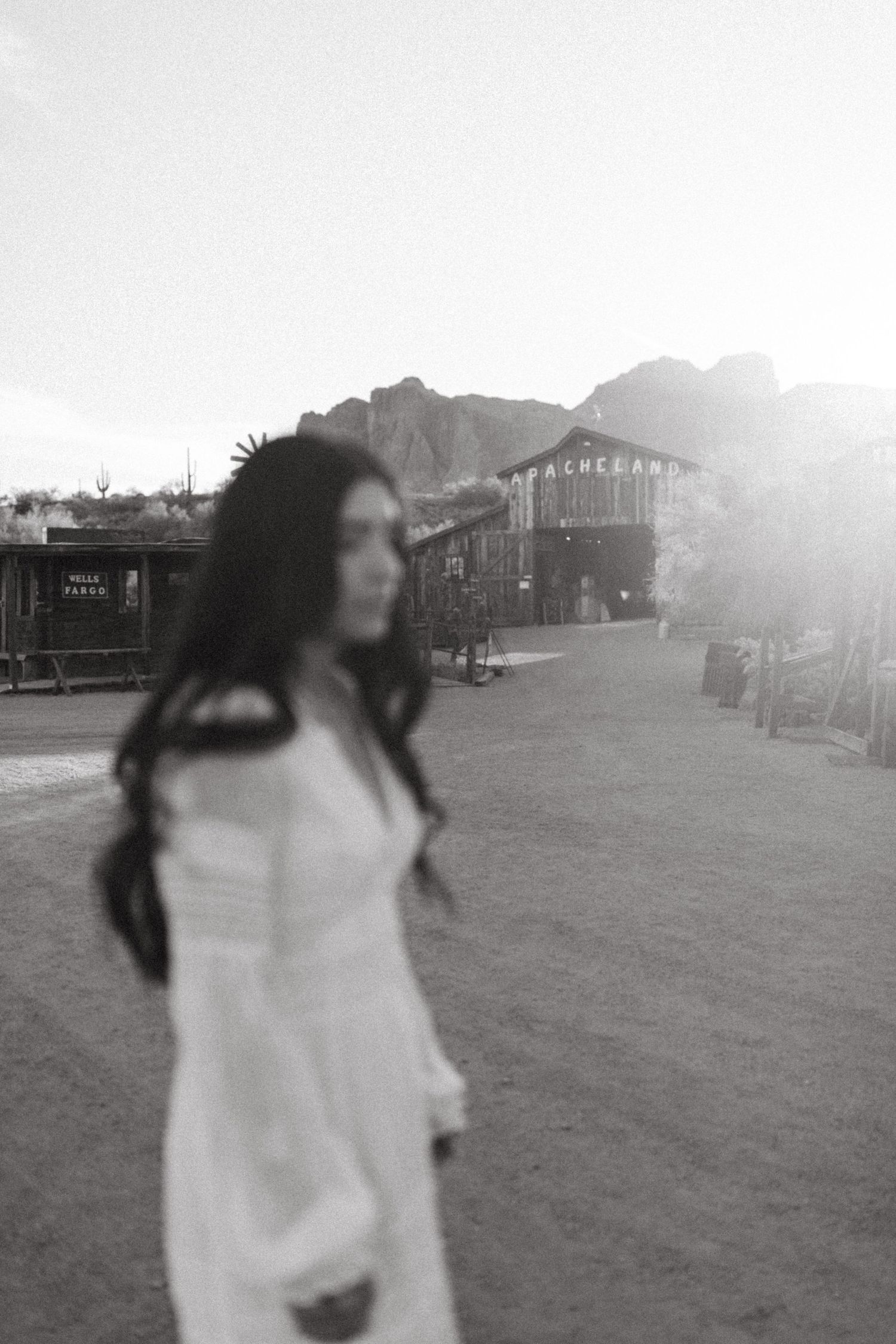 A figure in white spins in a dramatic dance motion across an open field with buildings visible in the distance.