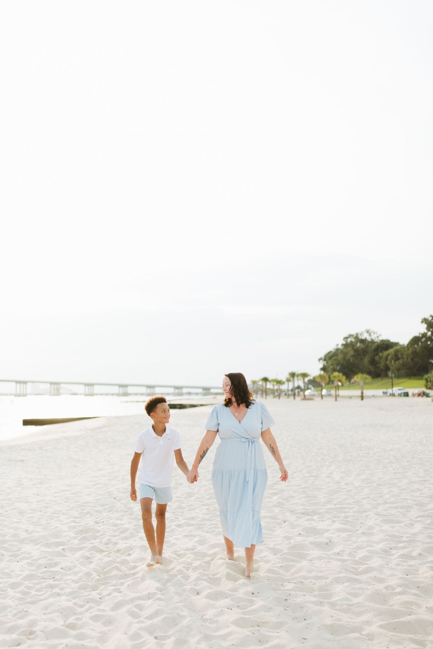 Family members walking together and holding hands on a pristine white sandy beach.