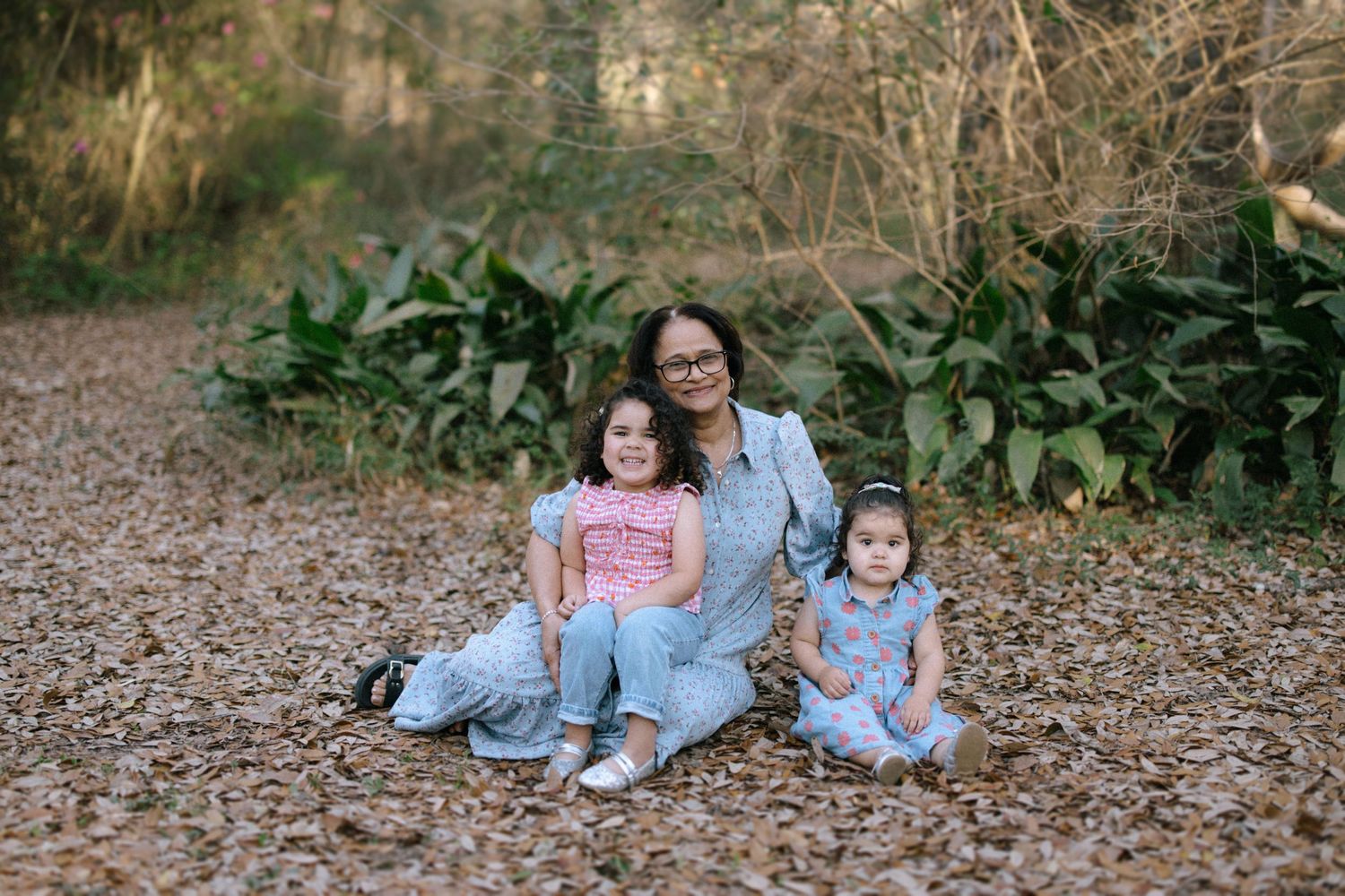 A cozy autumn portrait on fallen leaves with lush greenery in the background.