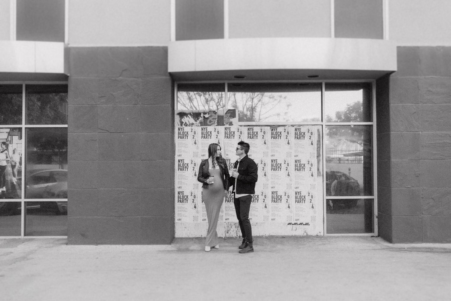 A black and white panoramic collage shows the exterior of a building with glass windows and poster displays.