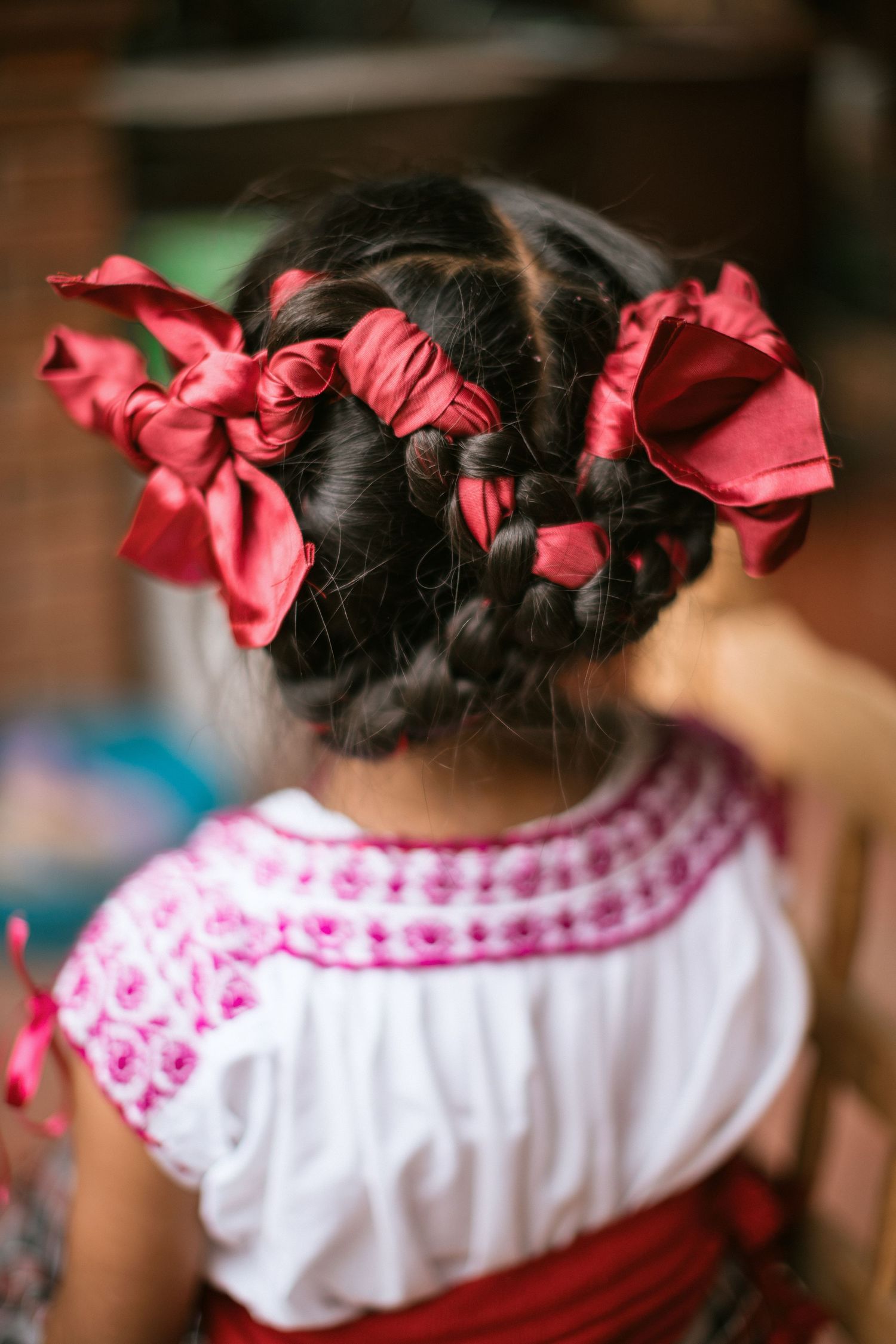 Four photos showing traditional Indian-style braided hairstyles with bright red ribbons and a white and pink patterned top.