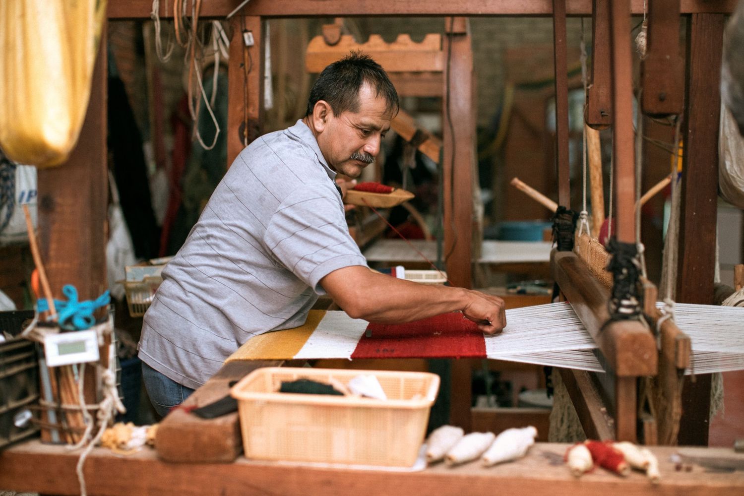 Woodworking expert shapes timber on a lathe in a rustic workshop filled with traditional tools and machinery.