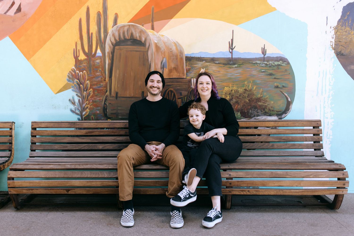 Two people share a happy moment while sitting together on a wooden bench at a park.